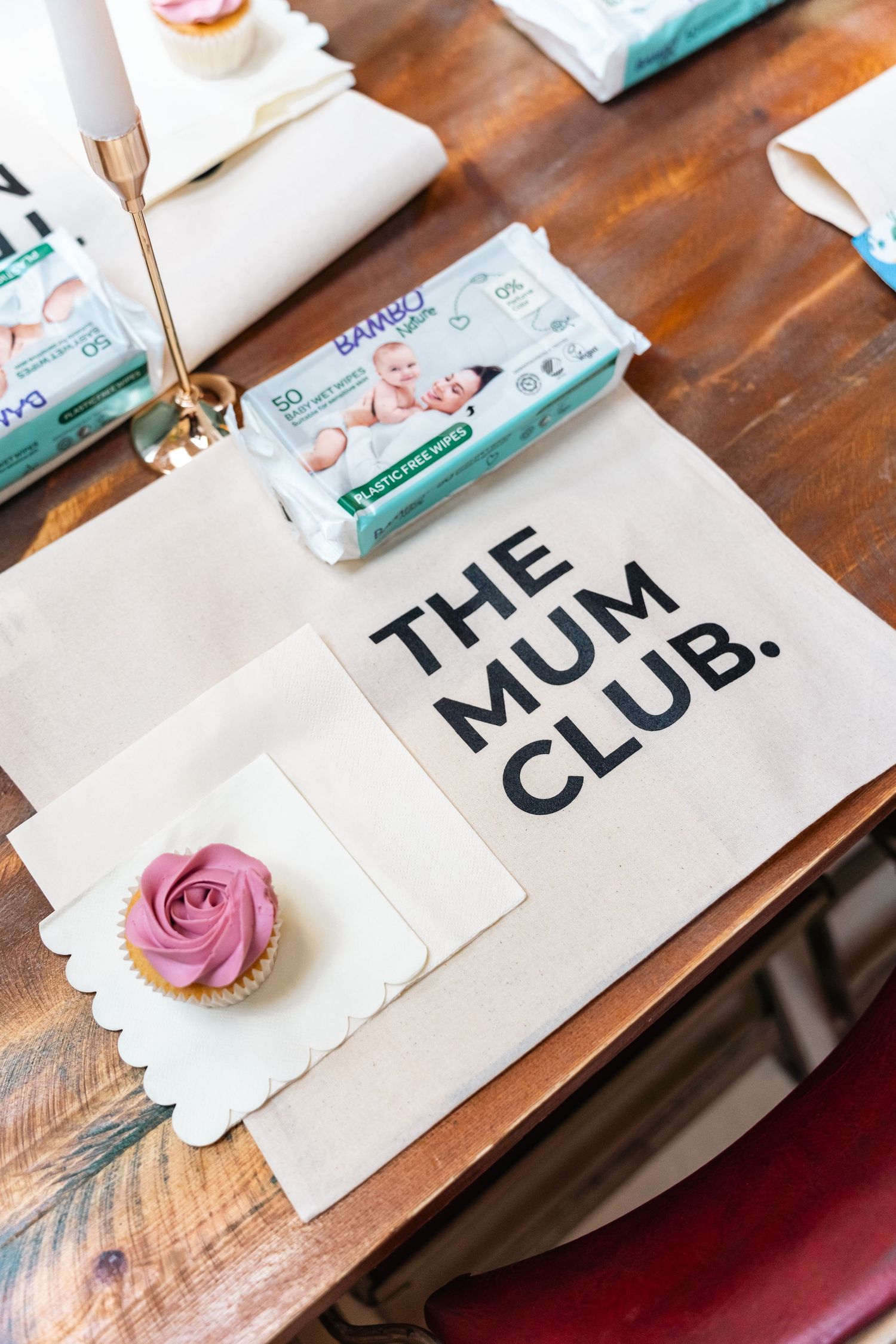 Pink cupcake frosting and name cards displayed on a wooden table for a wedding or event setup.