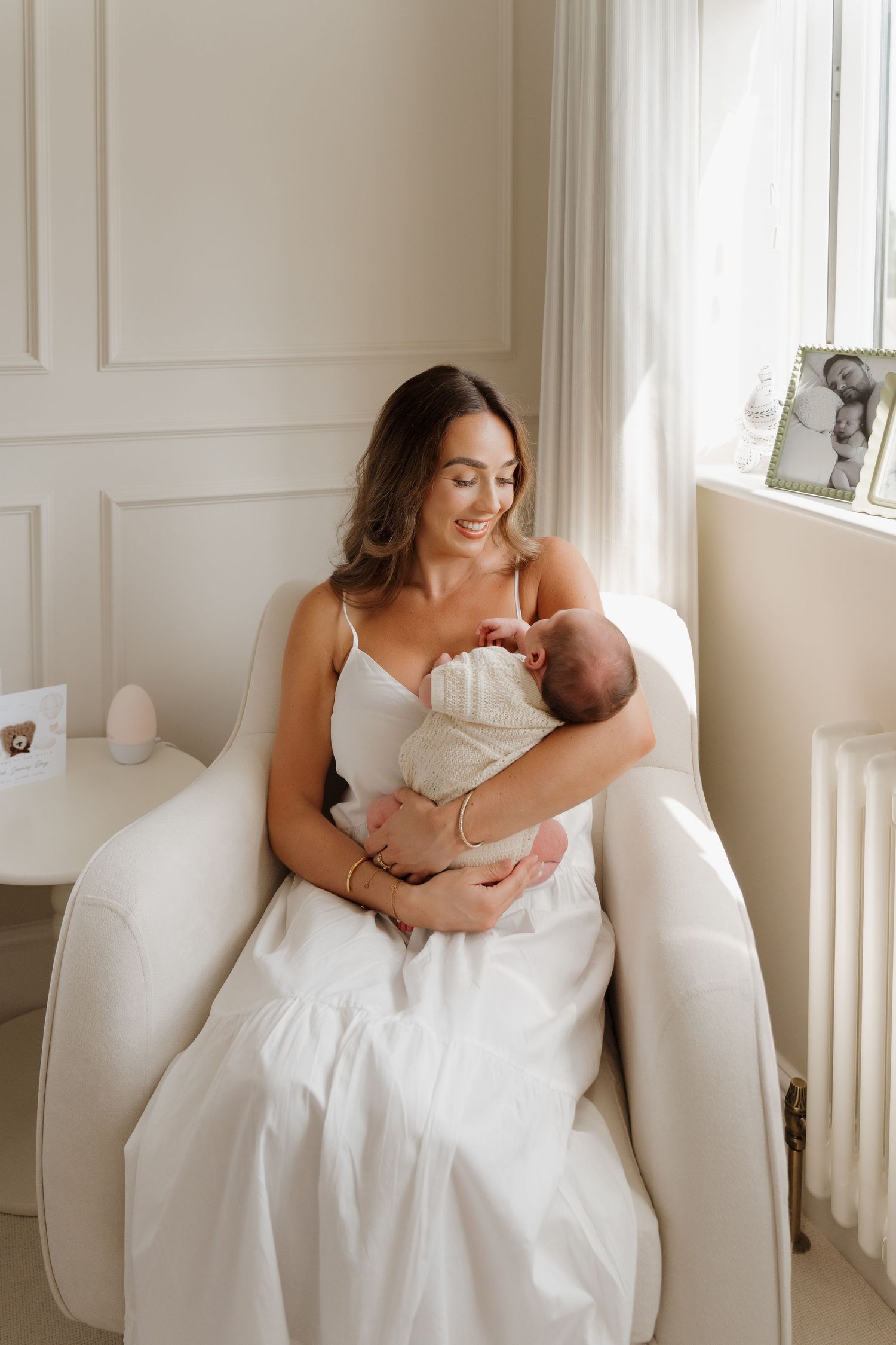 Intimate moments captured between a new mother and her baby by a bright window in their home, documentary home photography in Derbyshire.