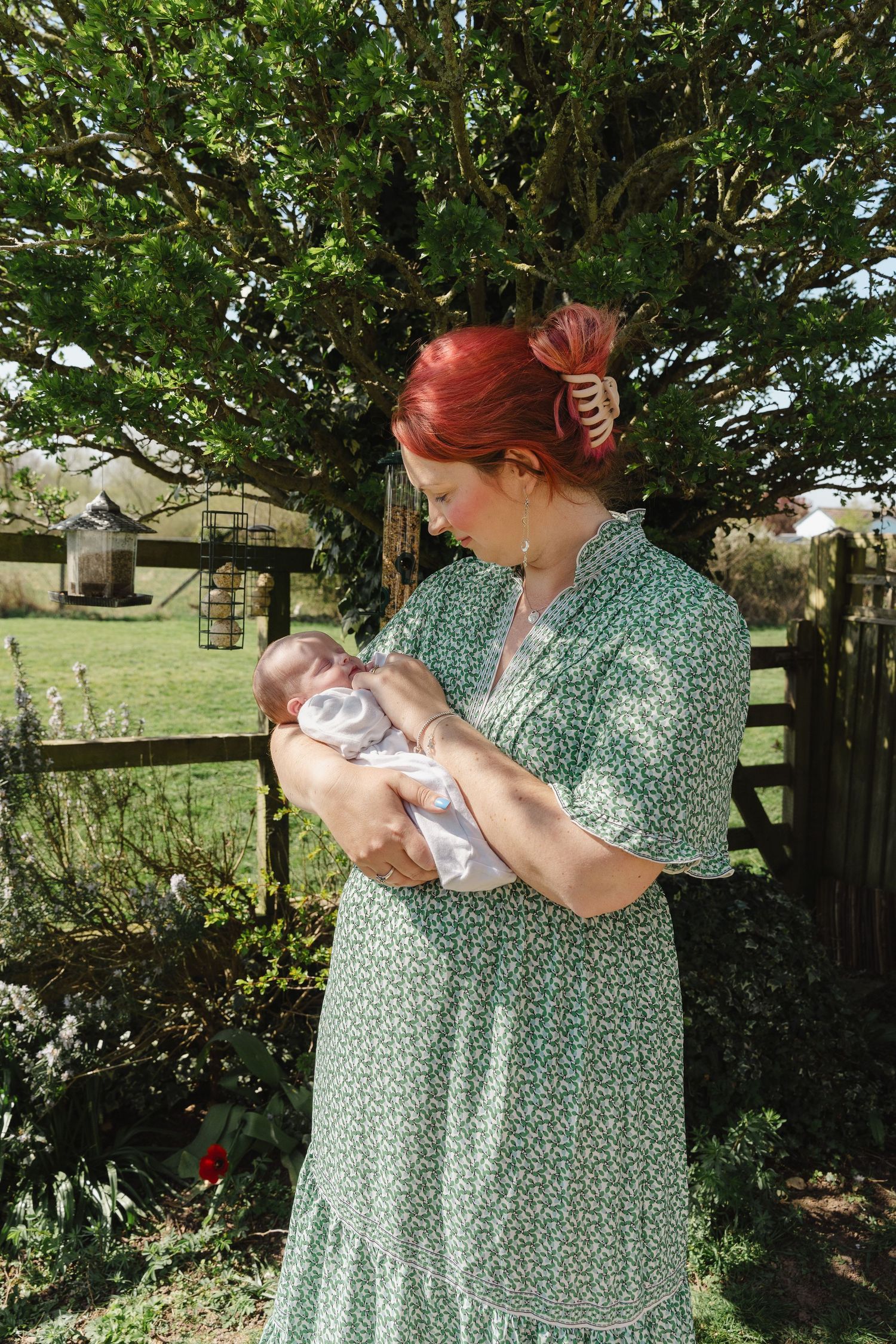 A sequence of outdoor photos showing someone in a green floral dress holding and cradling a small white bundle.