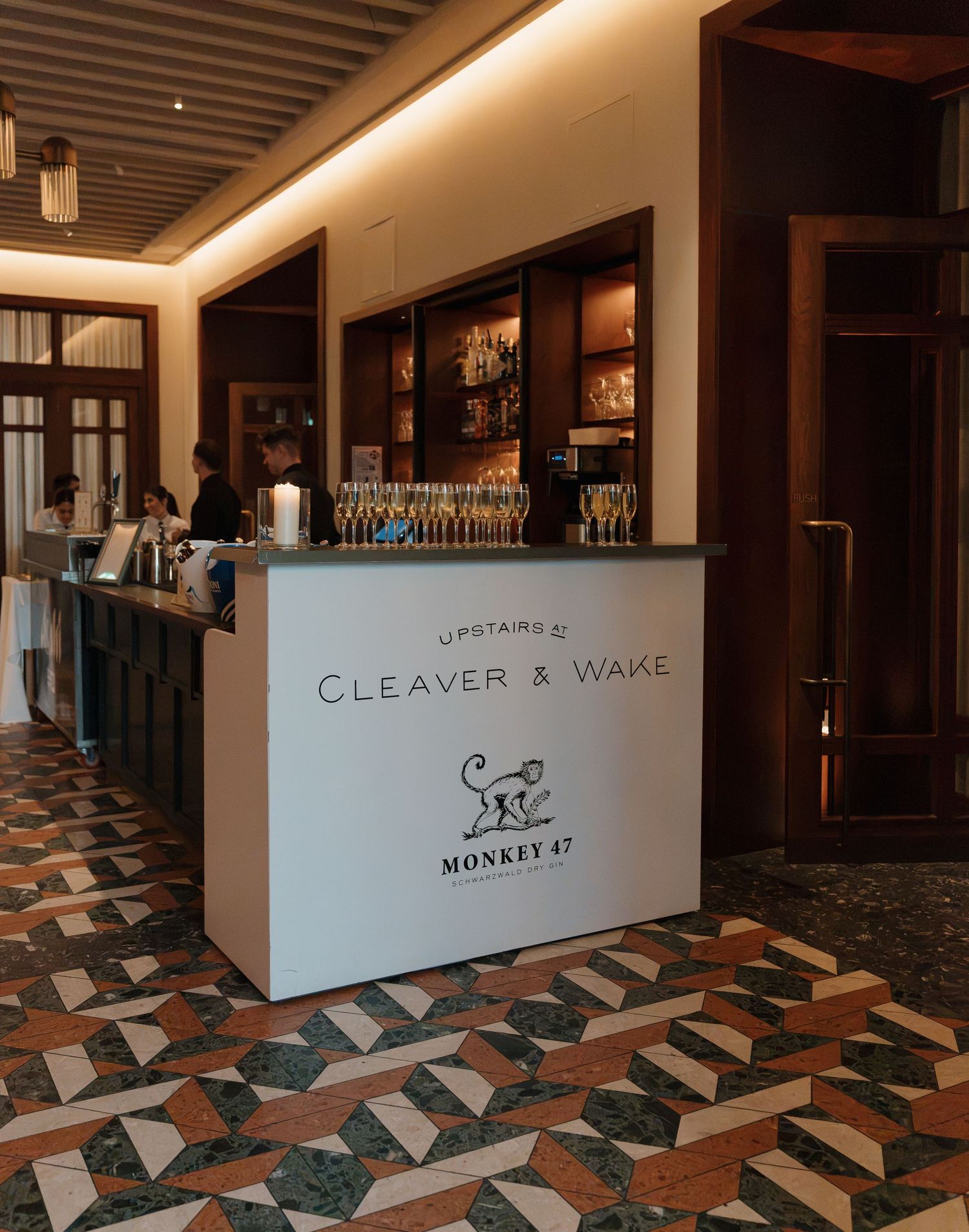 Upstairs at Cleaver & Wake bar featuring Monkey 47 gin branding, elegant mosaic floors, and warm ambient lighting.