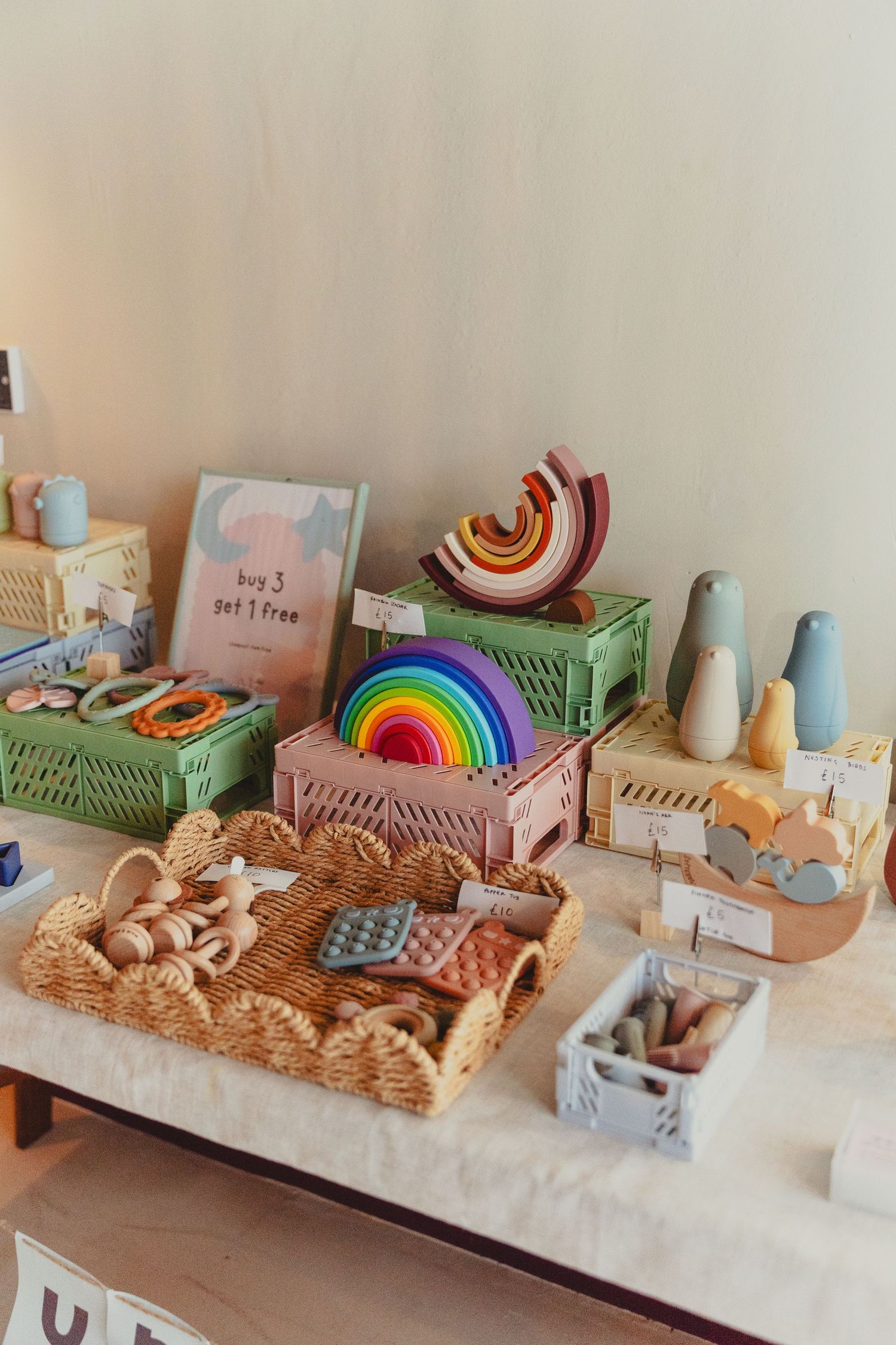 Montessori-style wooden toys and rainbow stacking blocks arranged on a neutral shelf with soft pastel colors and natural materials.