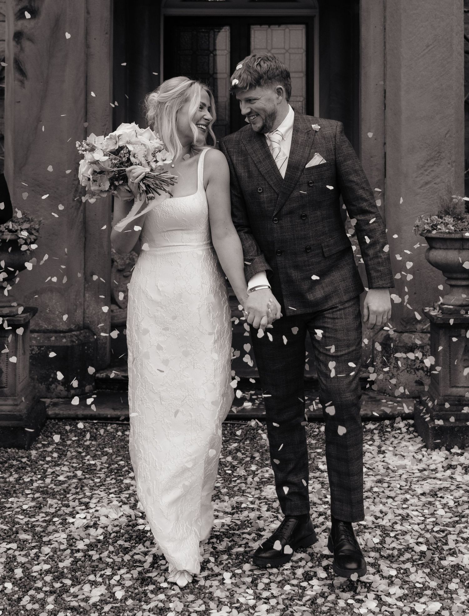 A wedding couple walks through a shower of white confetti in a sequence of black and white photographs.