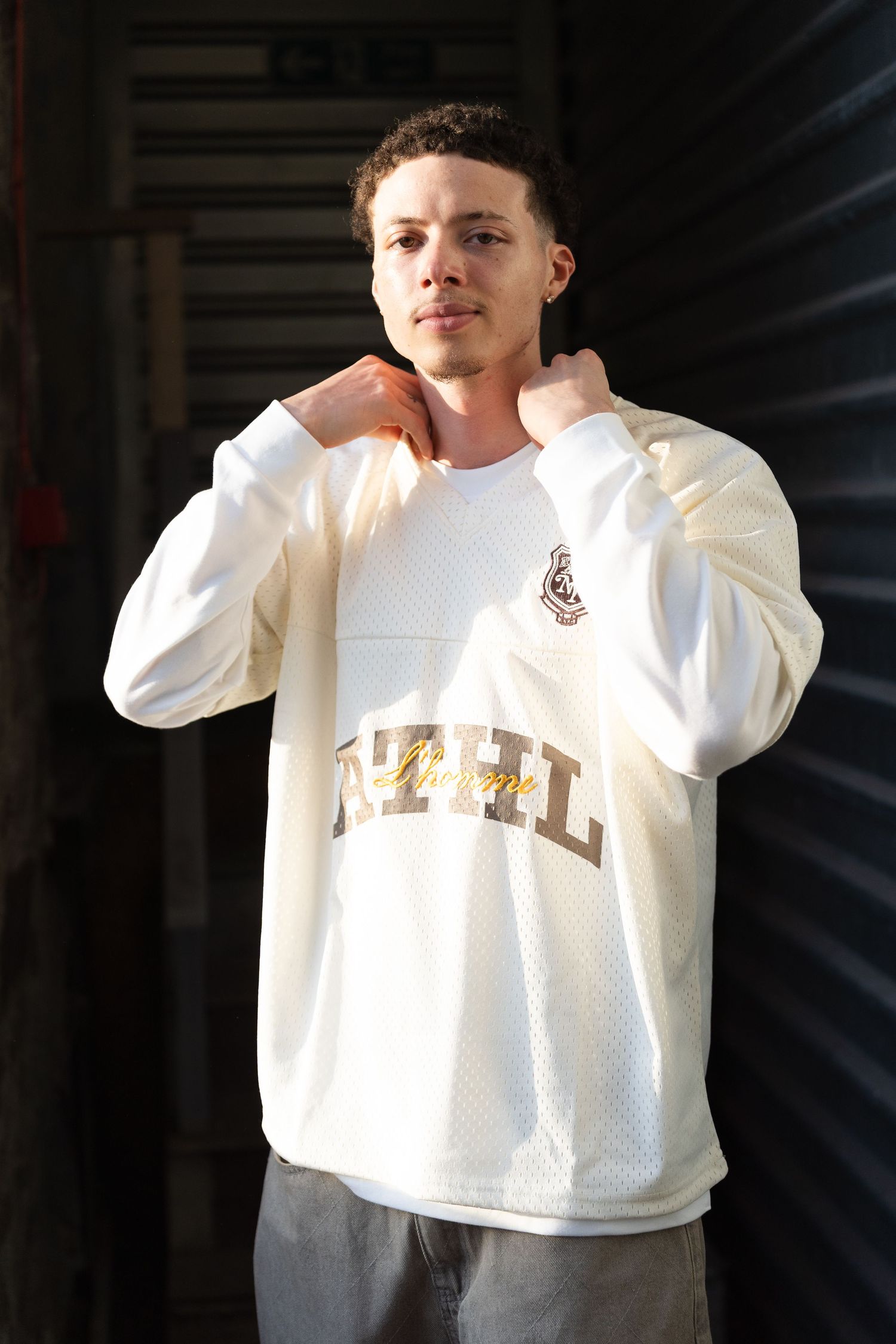 White mesh athletic sweatshirt shown from different angles in a dark studio setting.