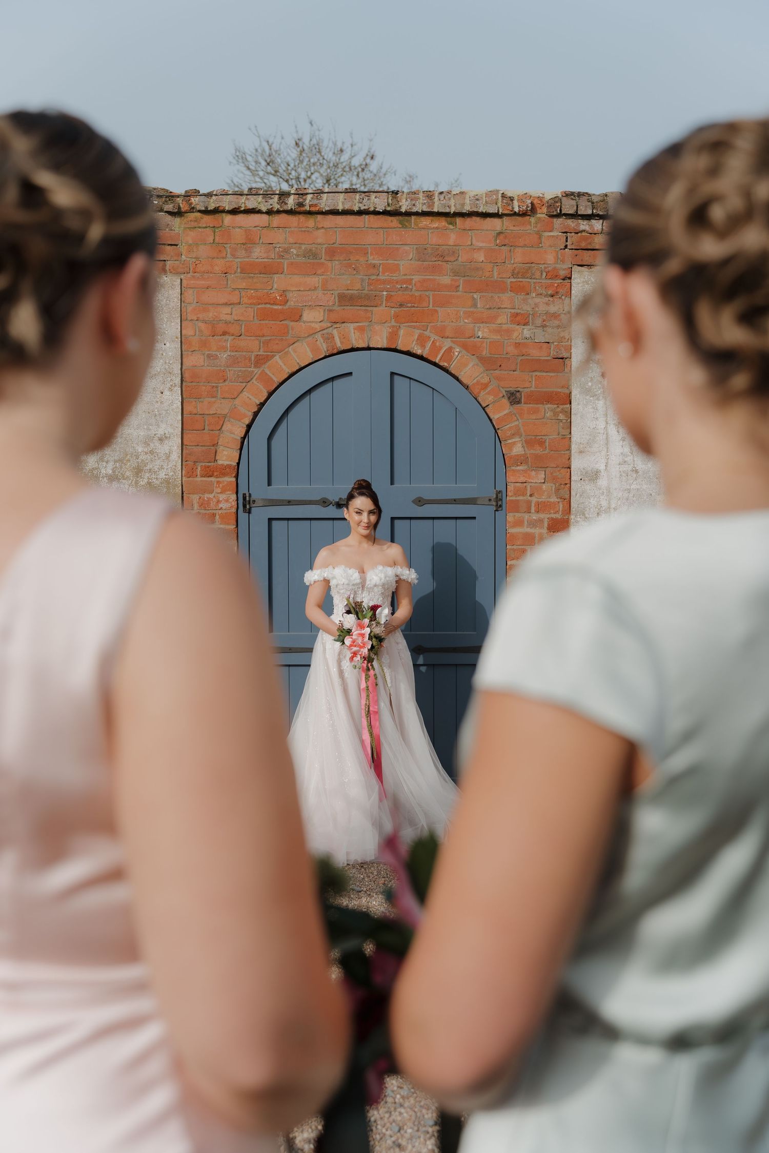 A series of candid wedding photos showing bridesmaids in soft mint dresses watching the bride pose against a brick wall.