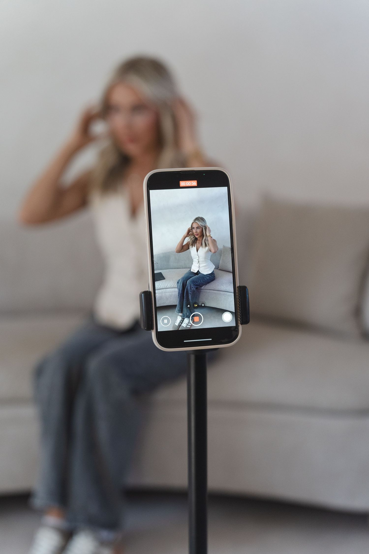 Phone mounted on stand displaying video call content with person sitting on couch in background.