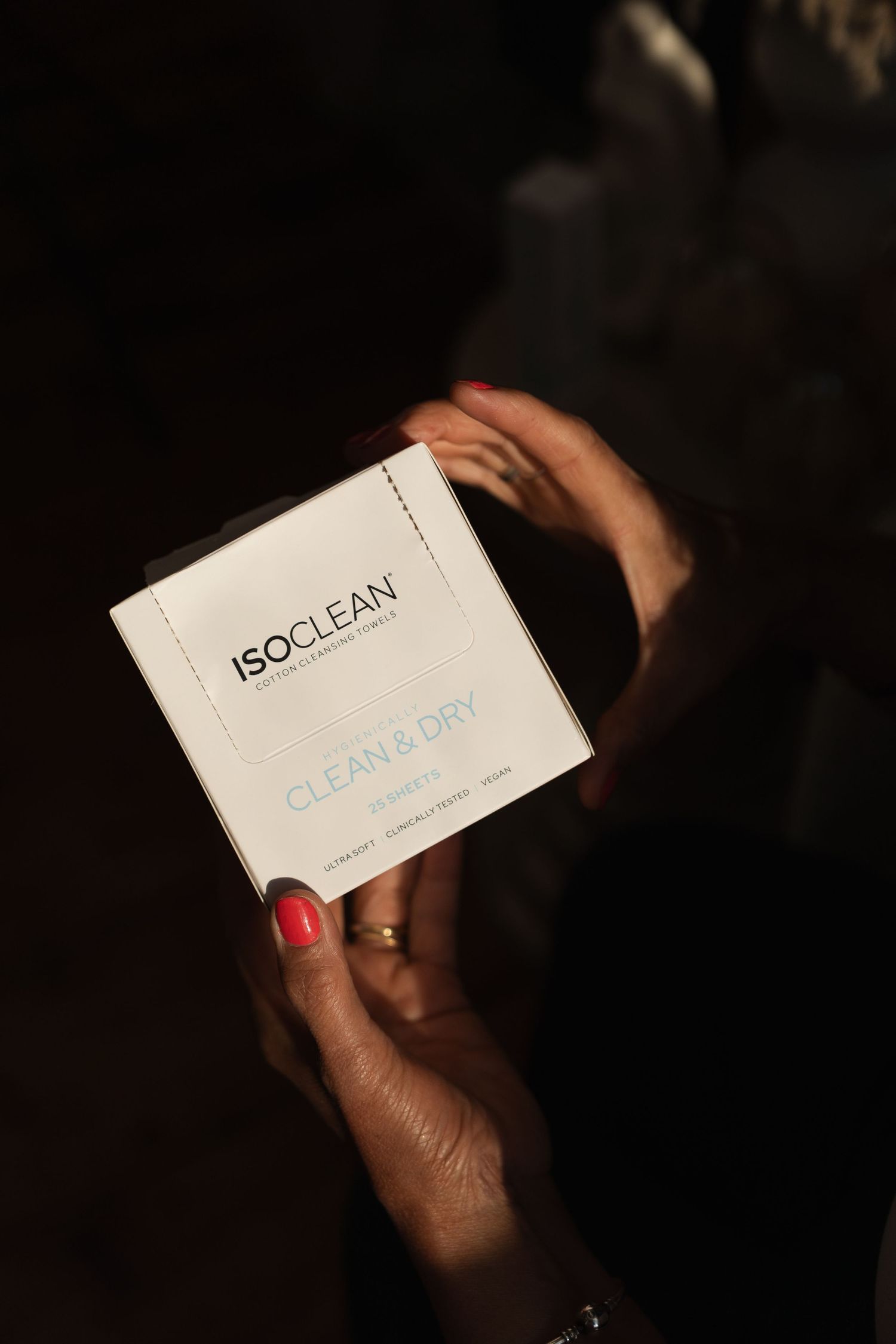 Hand holding a white business card or product card with 'ISOCLEAN' text against a dark background.