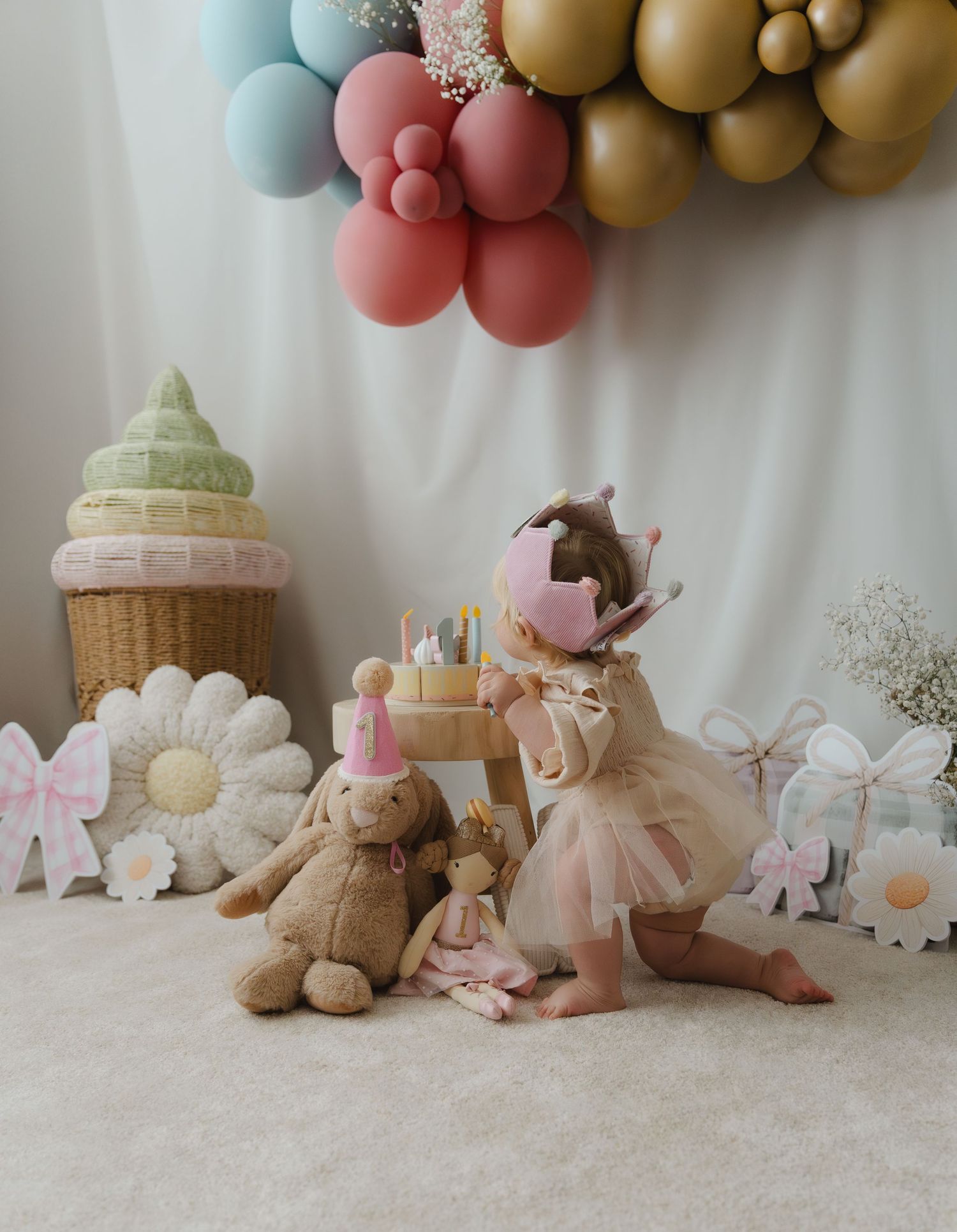 Soft pastel balloon arch with stuffed animals and pink decor creates a whimsical baby shower or birthday party setup.