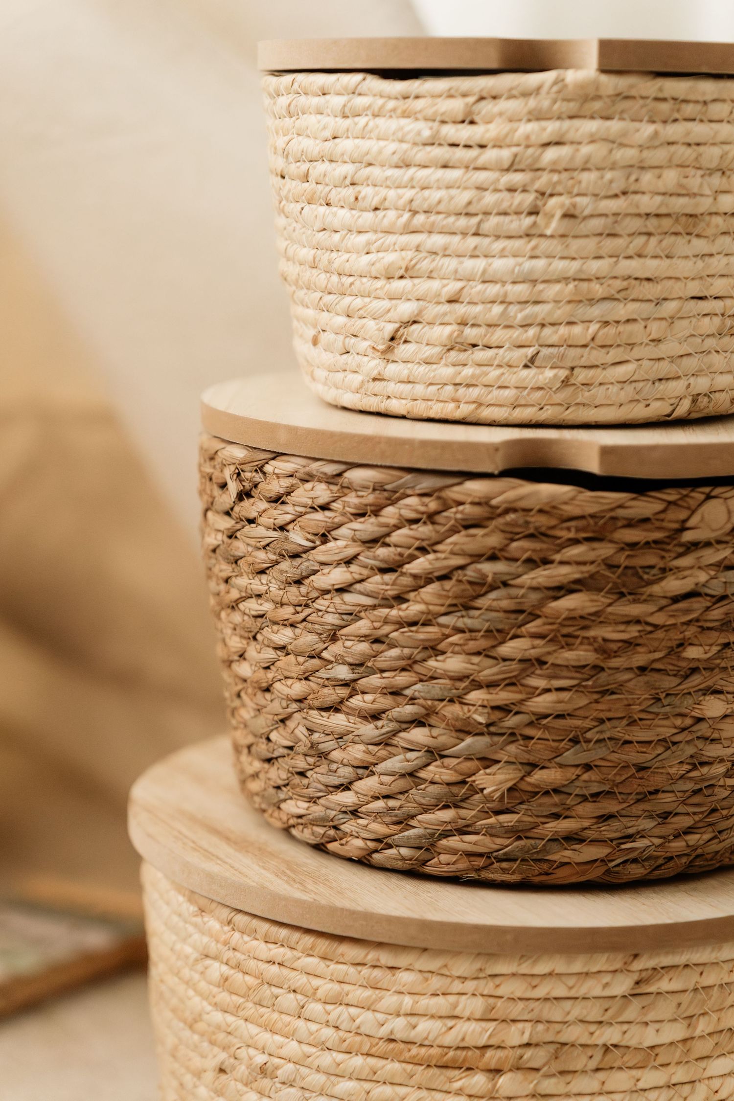 Coiled natural rope or twine on wooden spools arranged in a row with soft beige background lighting.