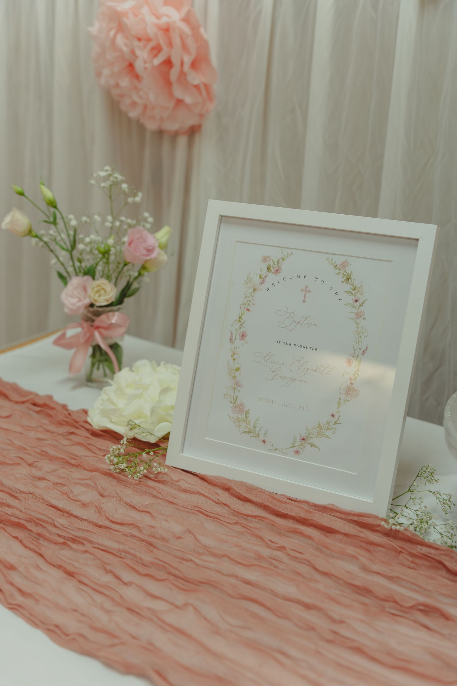 Elegant wedding table decor with pink ruffled tablecloth, white framed signs, and delicate floral arrangements.