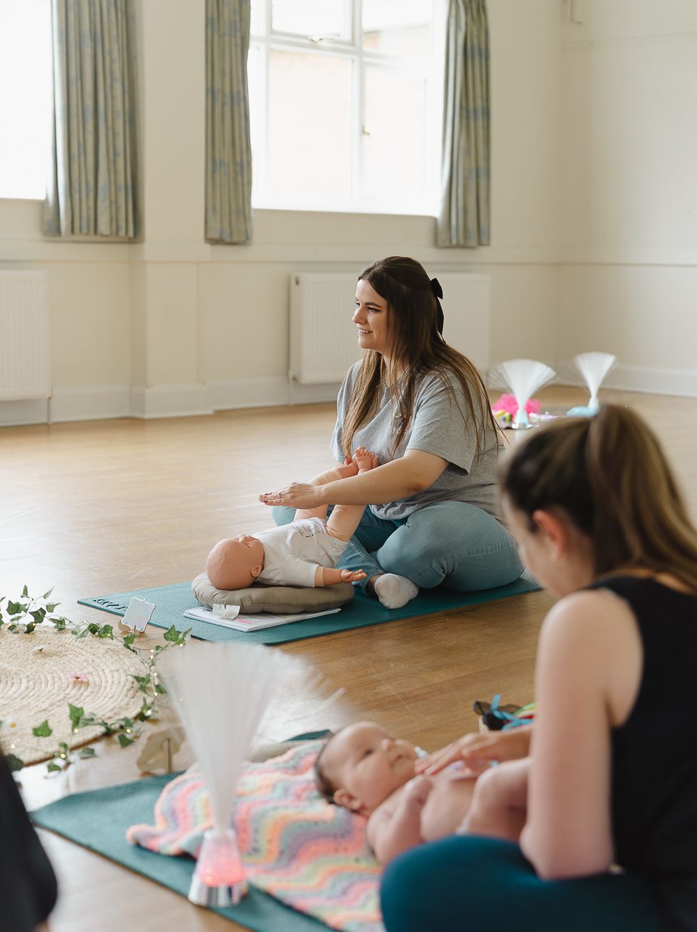 Parents and babies practicing yoga together on mats in a bright studio space during a mommy and me fitness class.