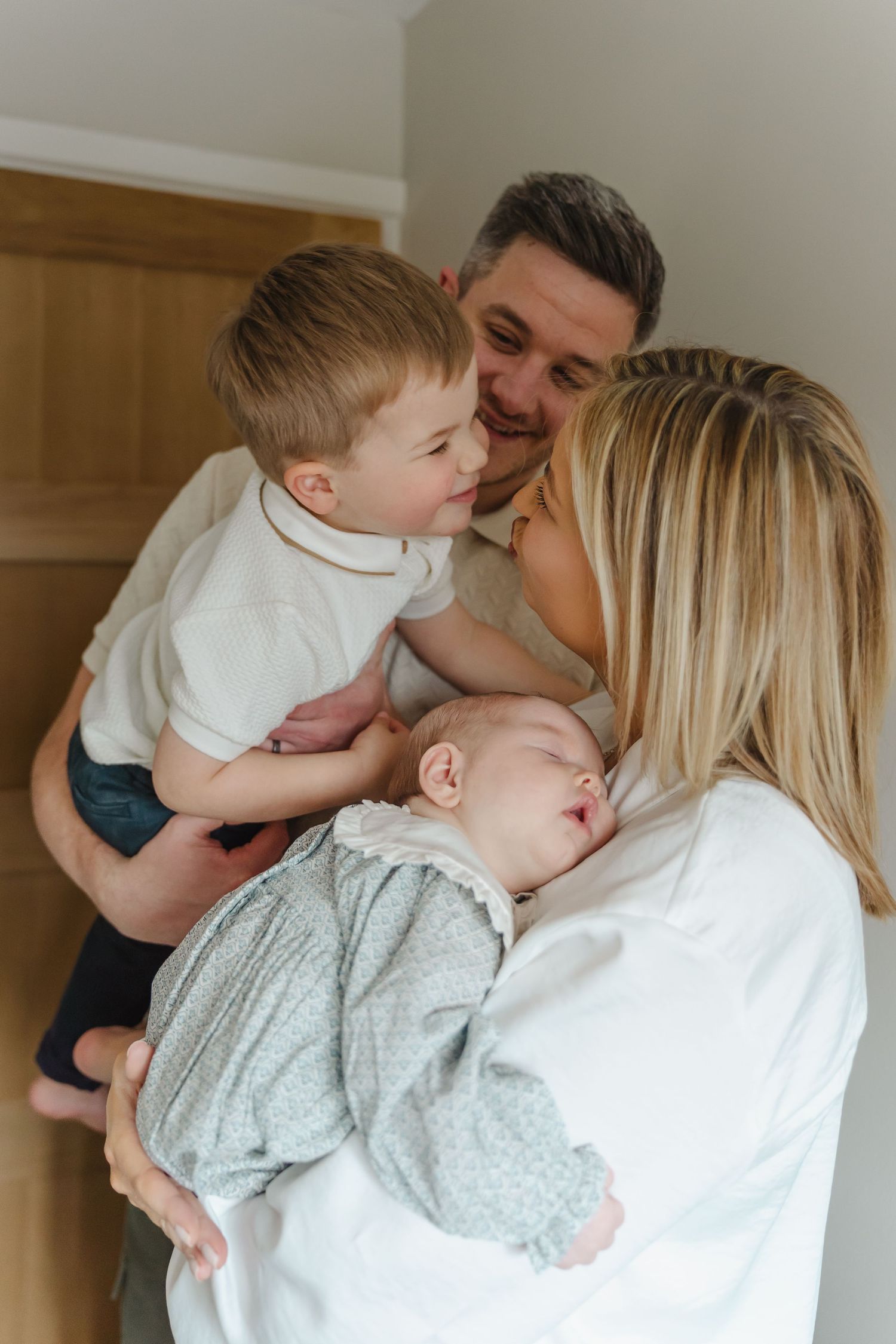 A loving family shares tender moments together in a series of intimate portrait photographs against a neutral background.