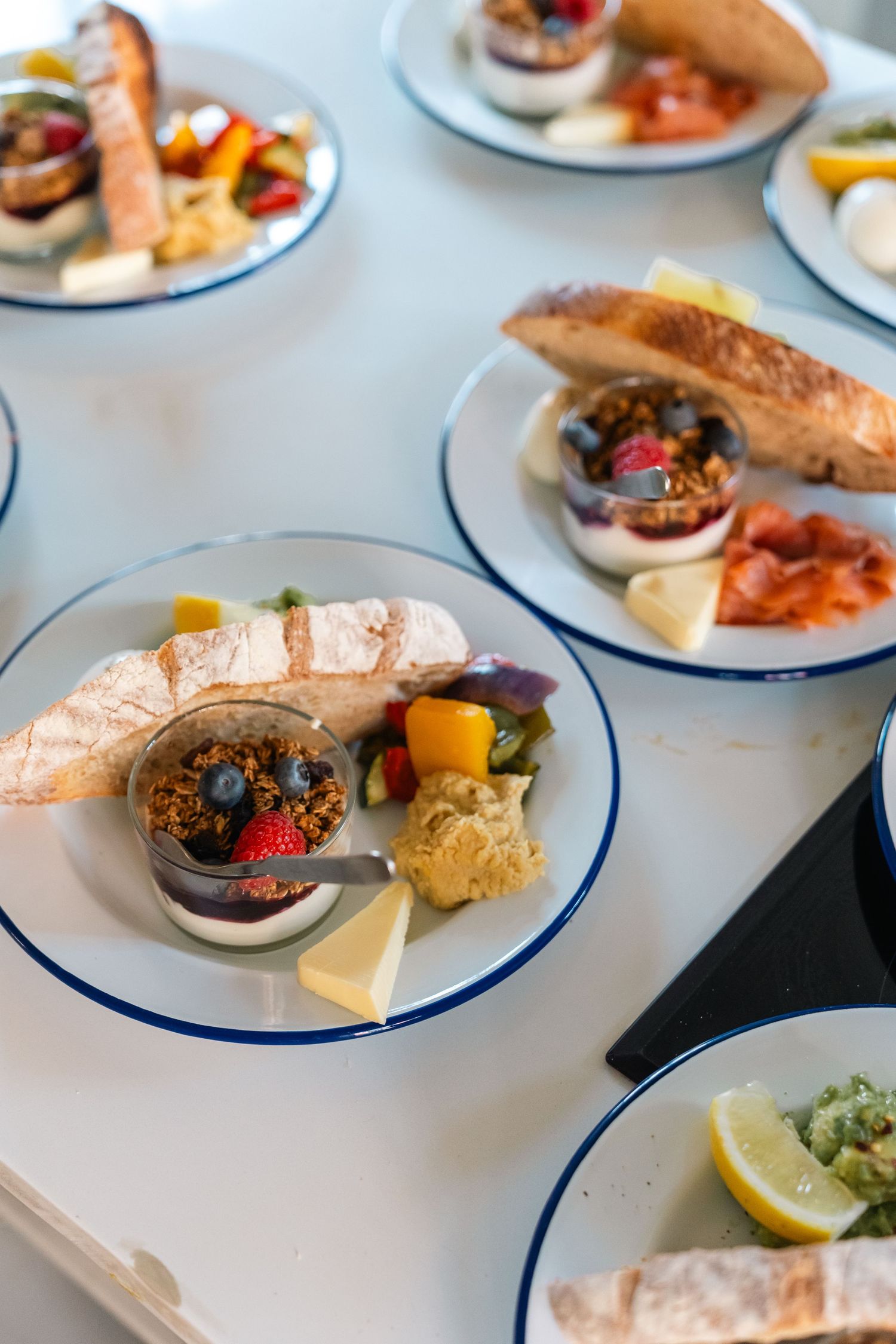 Multiple white plates with blue rims display elegant appetizers and seafood dishes in a restaurant setting.