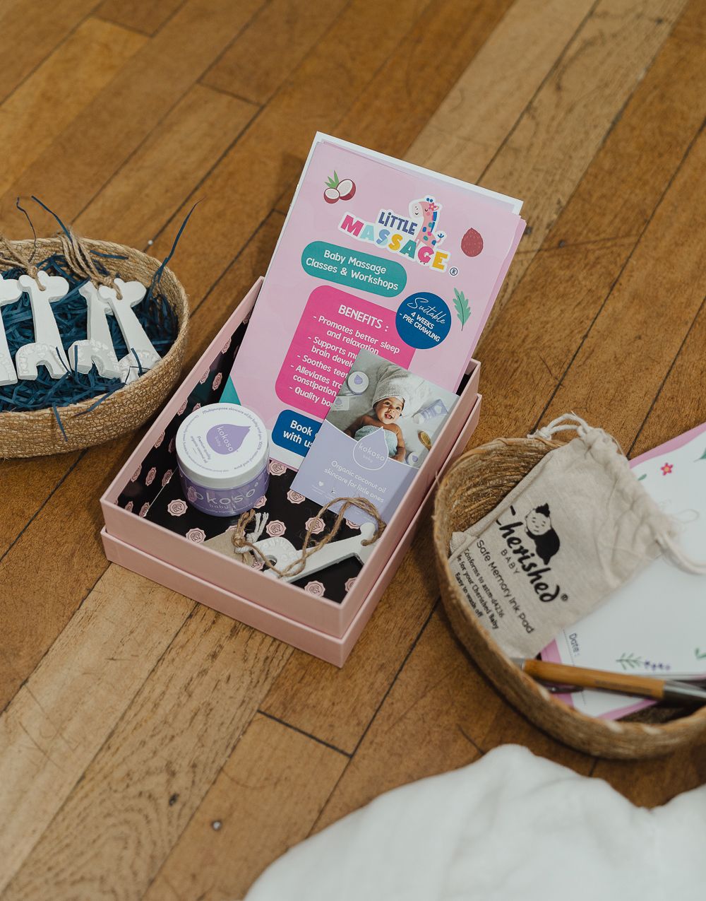 Baby products and accessories including bottles, pacifiers, and pink storage boxes arranged on a wooden floor.
