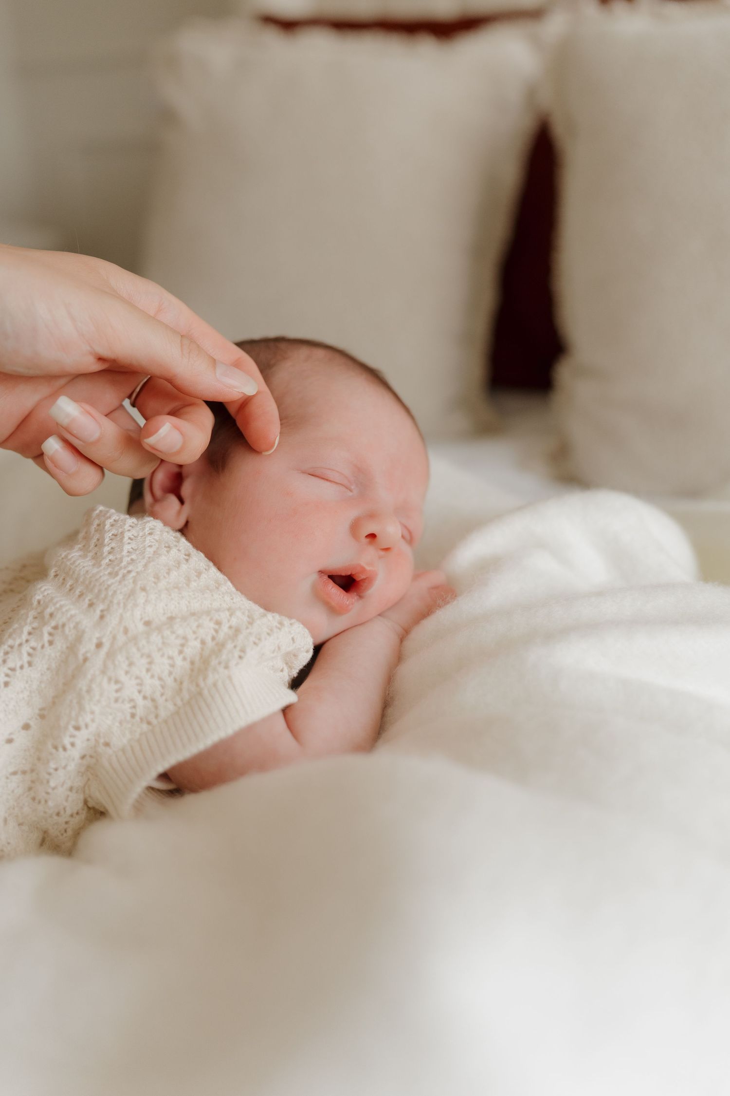 Close-up of a sleeping newborn wrapped in soft white blankets.