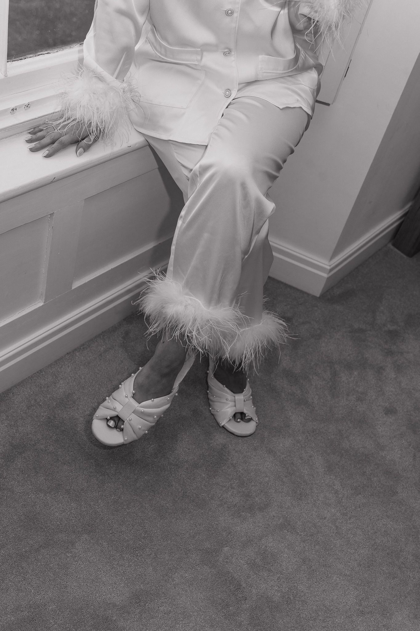 Detail shot of white feather-trimmed slippers and dress hem.