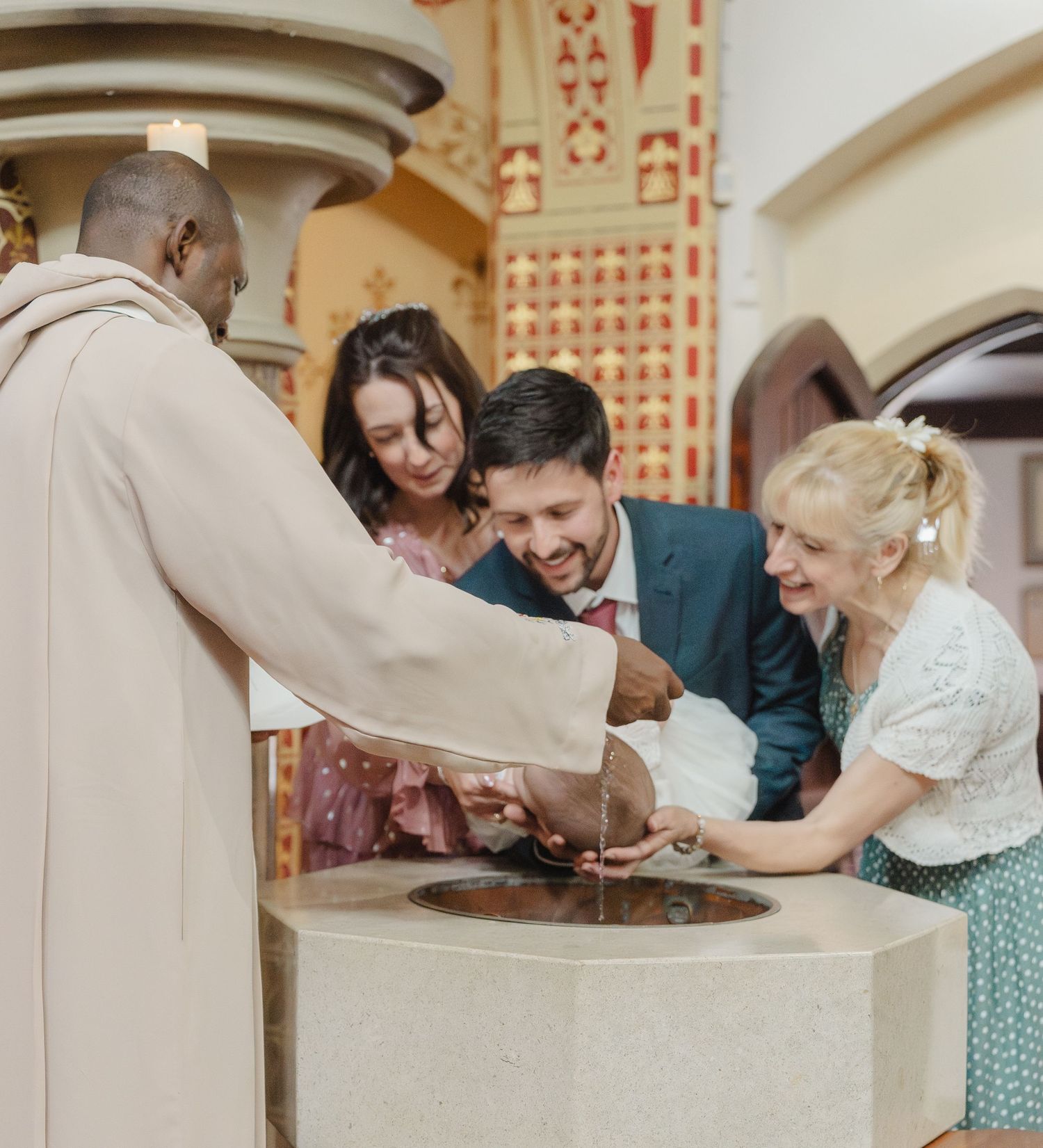 A group of people gather around a baptismal font in a church during a religious ceremony / christening in Derbyshire.