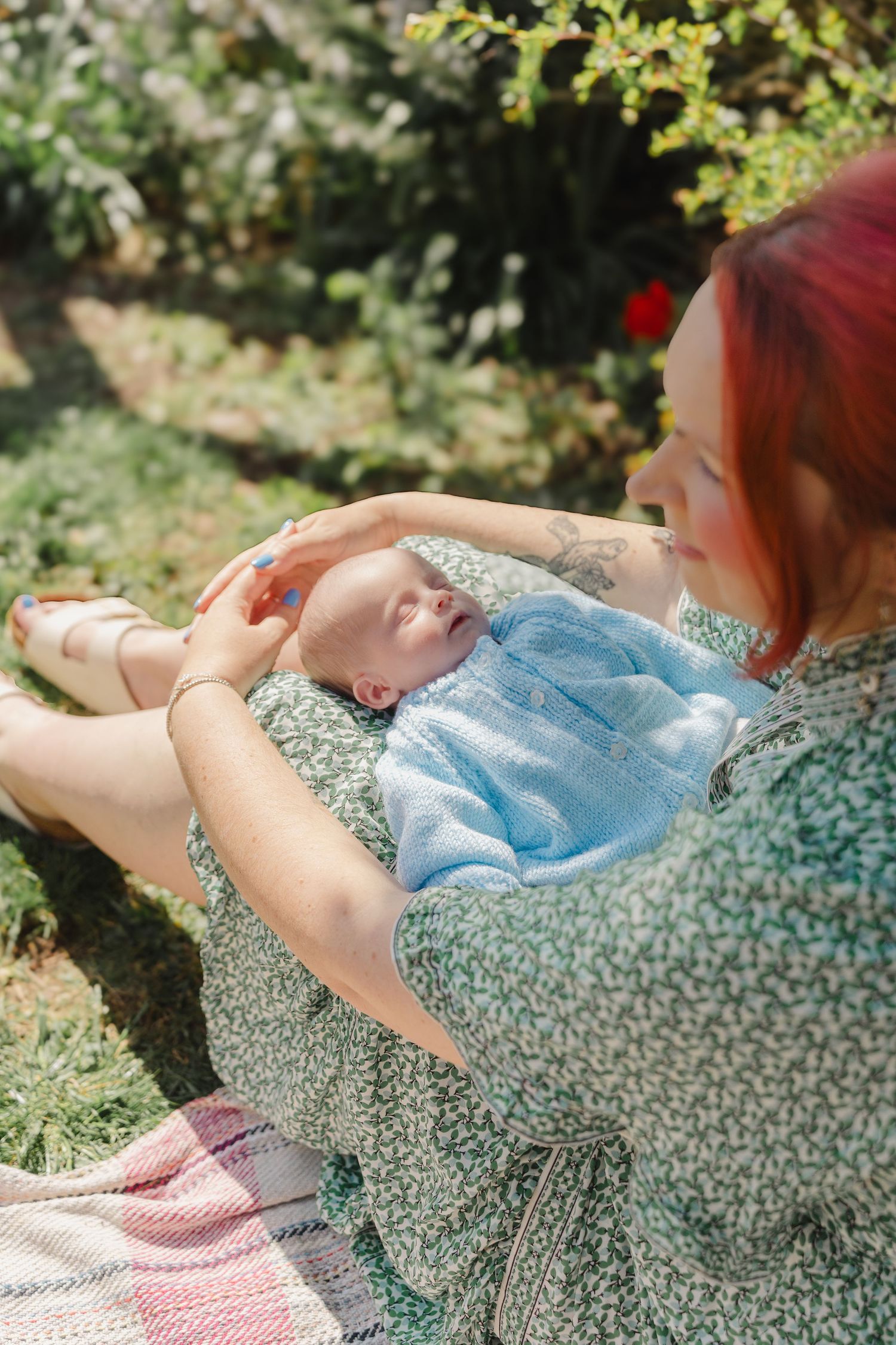 A person in a floral dress lying on a blanket outdoors enjoying a sunny day in nature.