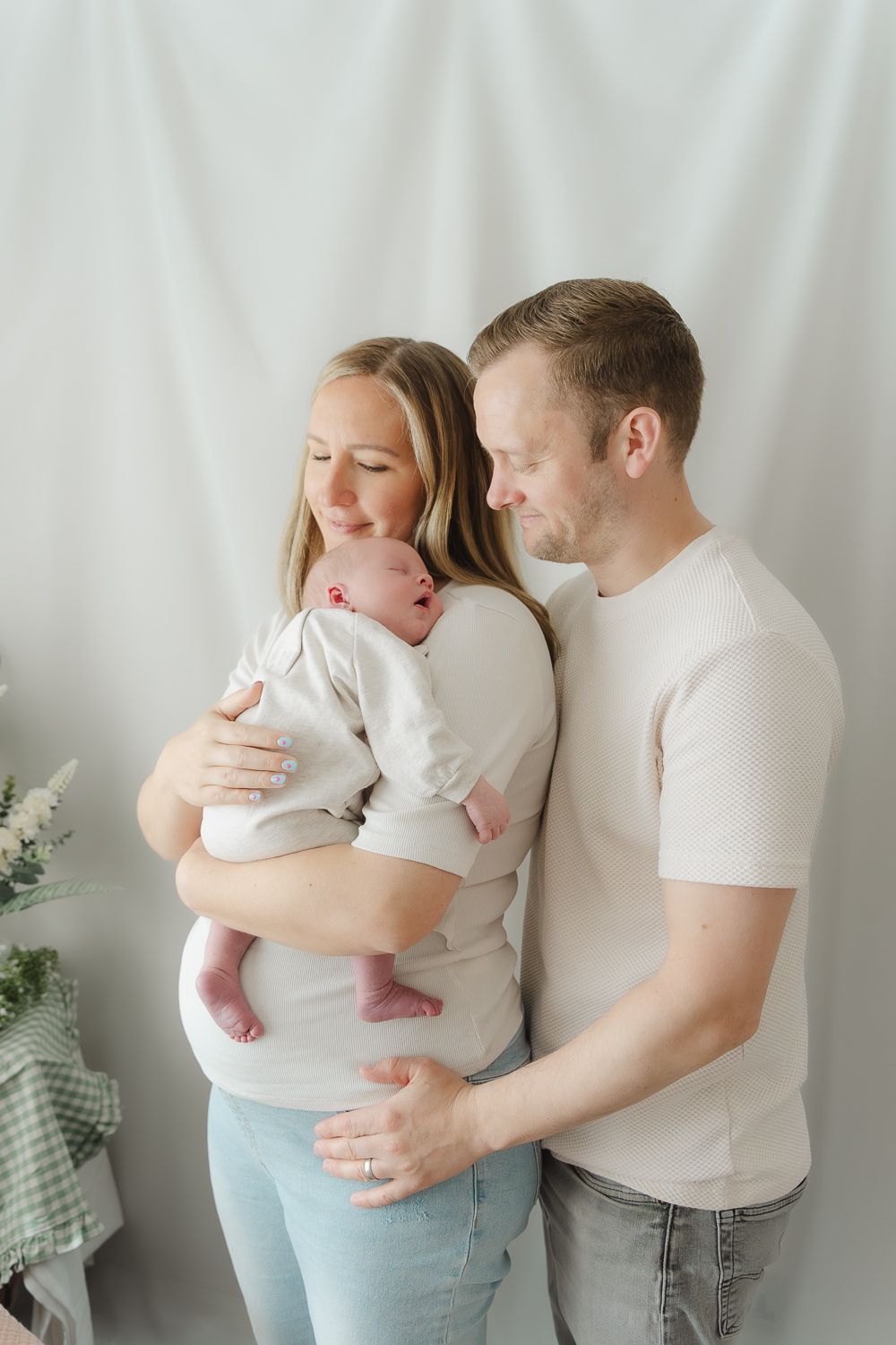 Family photoshoot featuring tender moments with a baby against white backdrop.