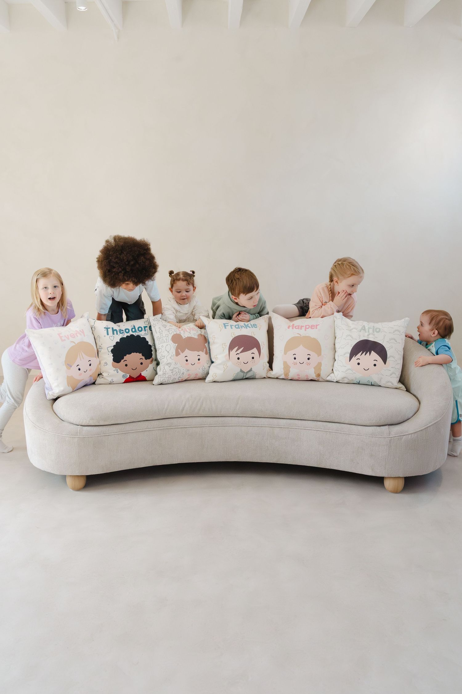 Long curved bench decorated with multiple character-themed pillows in soft pastel colors.