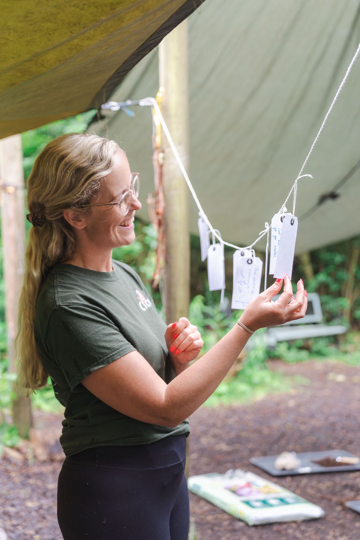 Person practicing target shooting with handgun at outdoor range while wearing protective gear and green shirt.