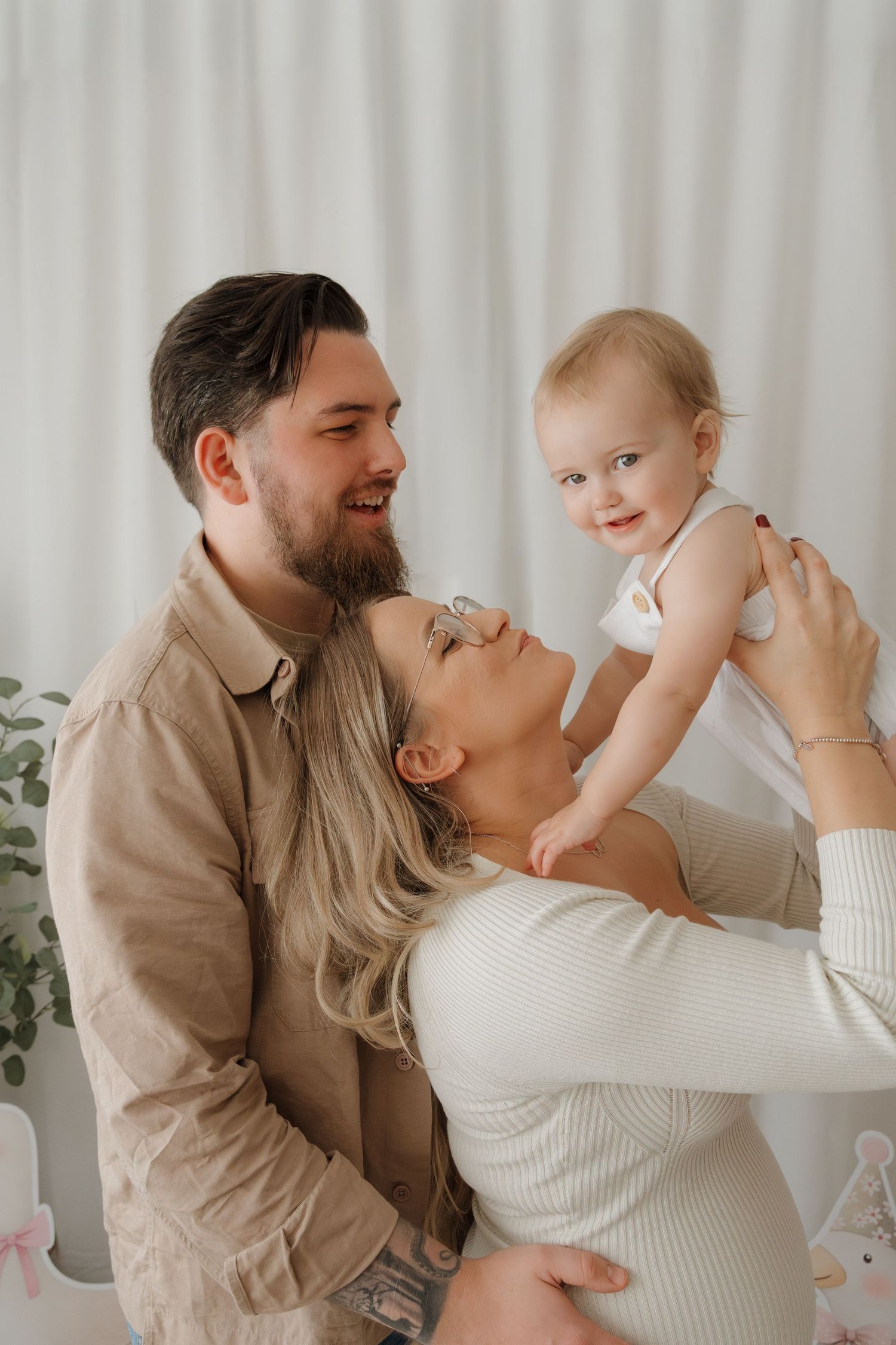Family enjoying tender moments together in a bright room with white curtains and natural lighting.