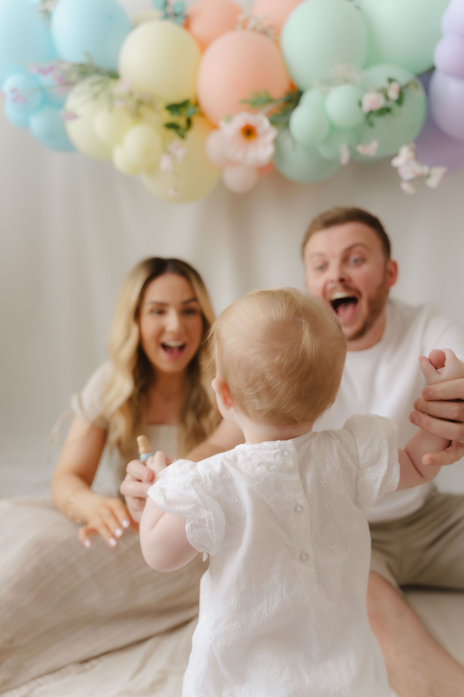 Family celebrates with pastel balloons and decorations in a bright, joyful indoor setting.