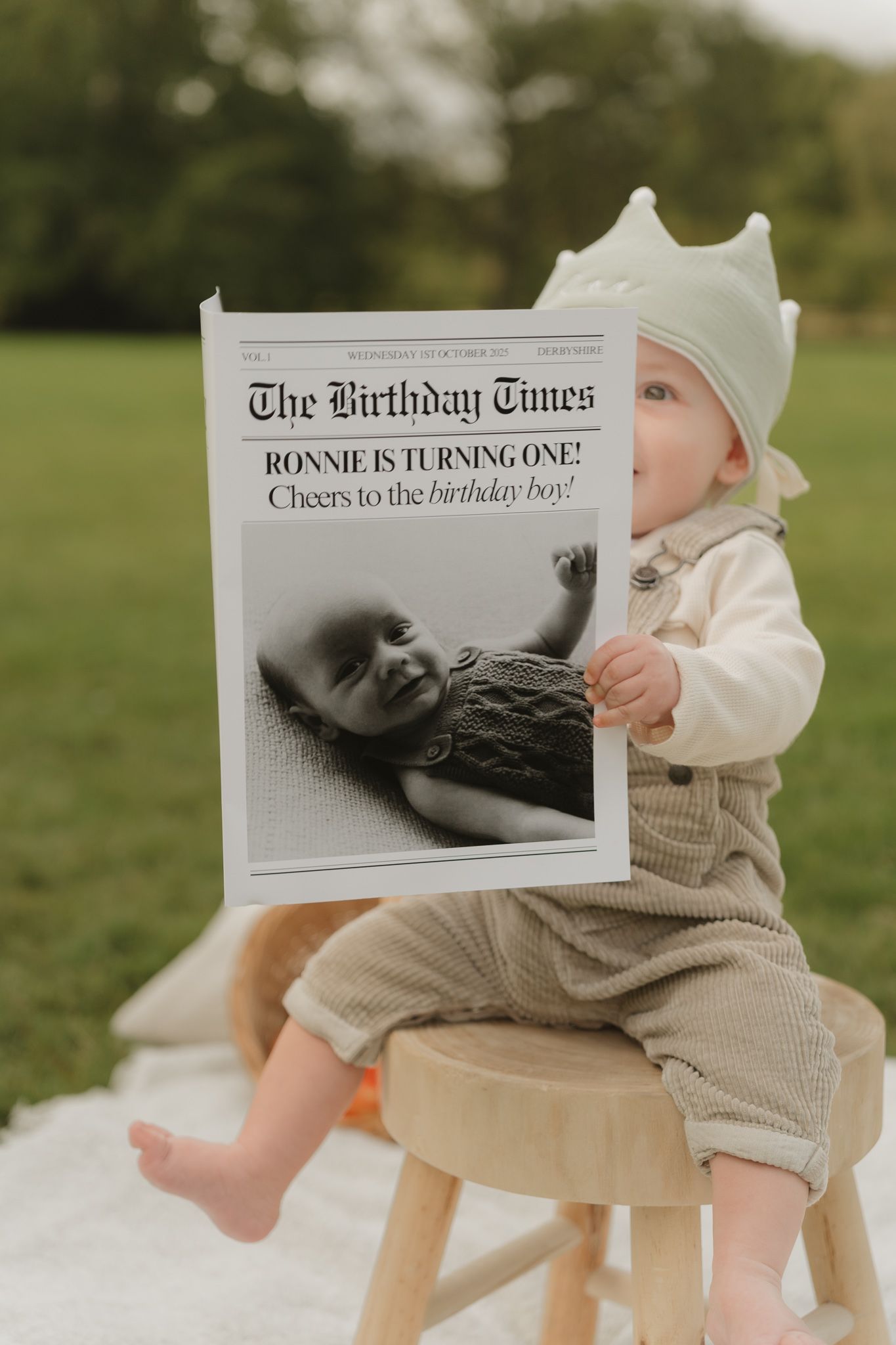 Custom newspaper-style birthday announcement displayed outdoors on grassy setting.