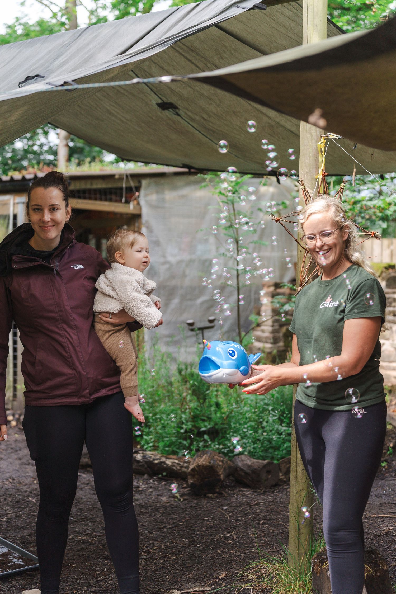 People playing with bubbles in an outdoor garden setting under a canopy.