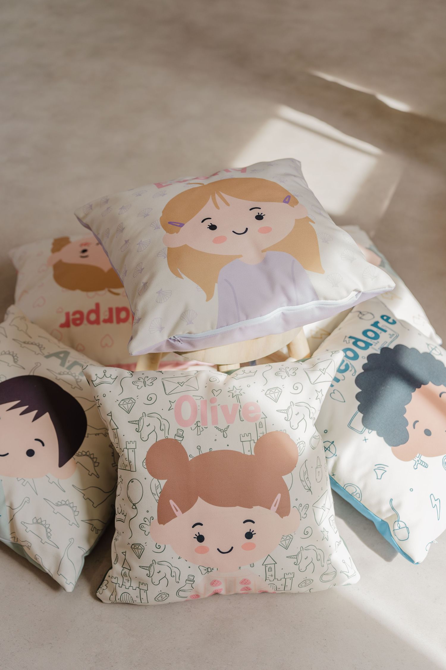 Cute cartoon character pillows with smiling faces arranged in a row against a neutral background.