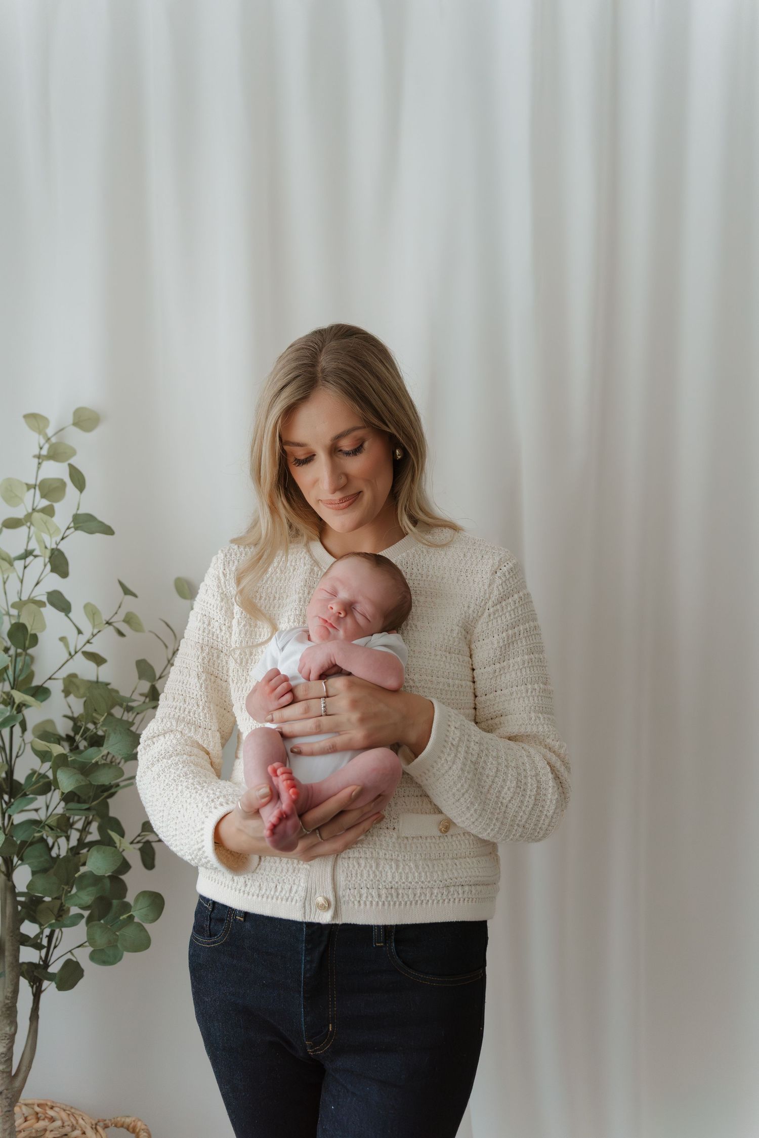 A tender moment captured in a series of photos showing a parent holding and cradling a newborn baby against a white backdrop.