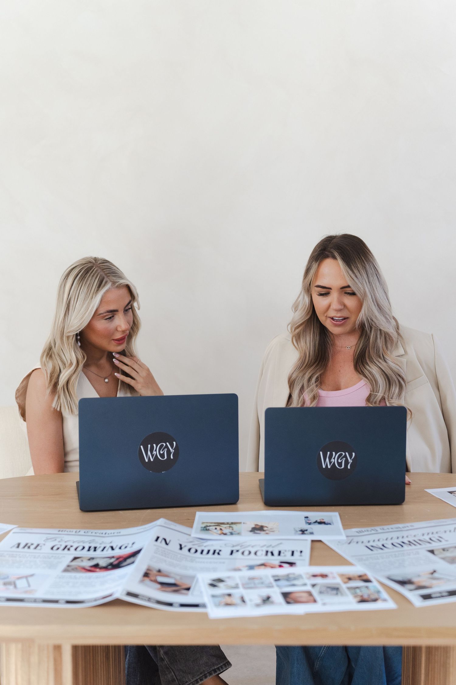 Person working at desk with laptop and printed marketing materials spread across white table surface.