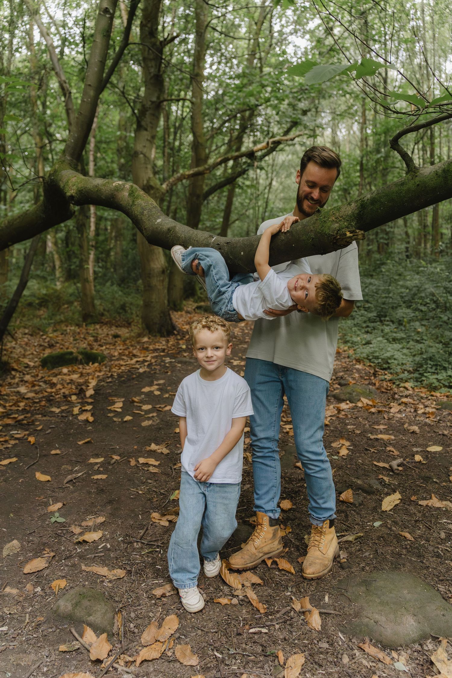 Family in casual denim outfits walking together through a wooded forest path on an autumn day.