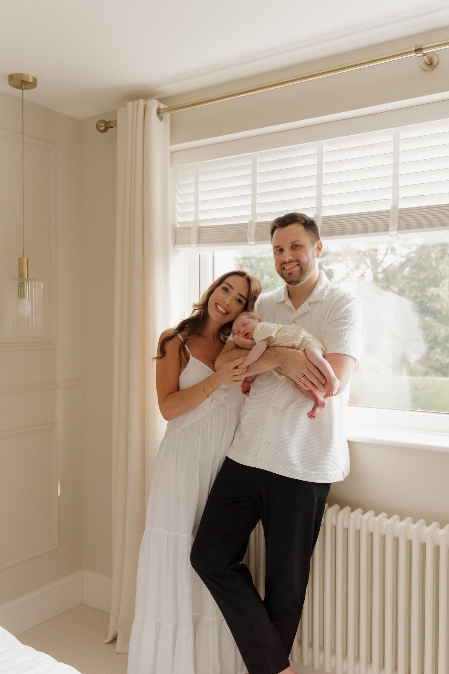 A joyful family moment with their newborn in a bright white room.