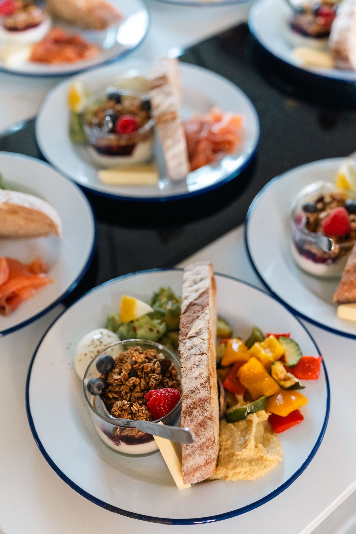 Elegant appetizer plates with navy blue rims display assorted hors d'oeuvres and fresh seafood at a catered event.