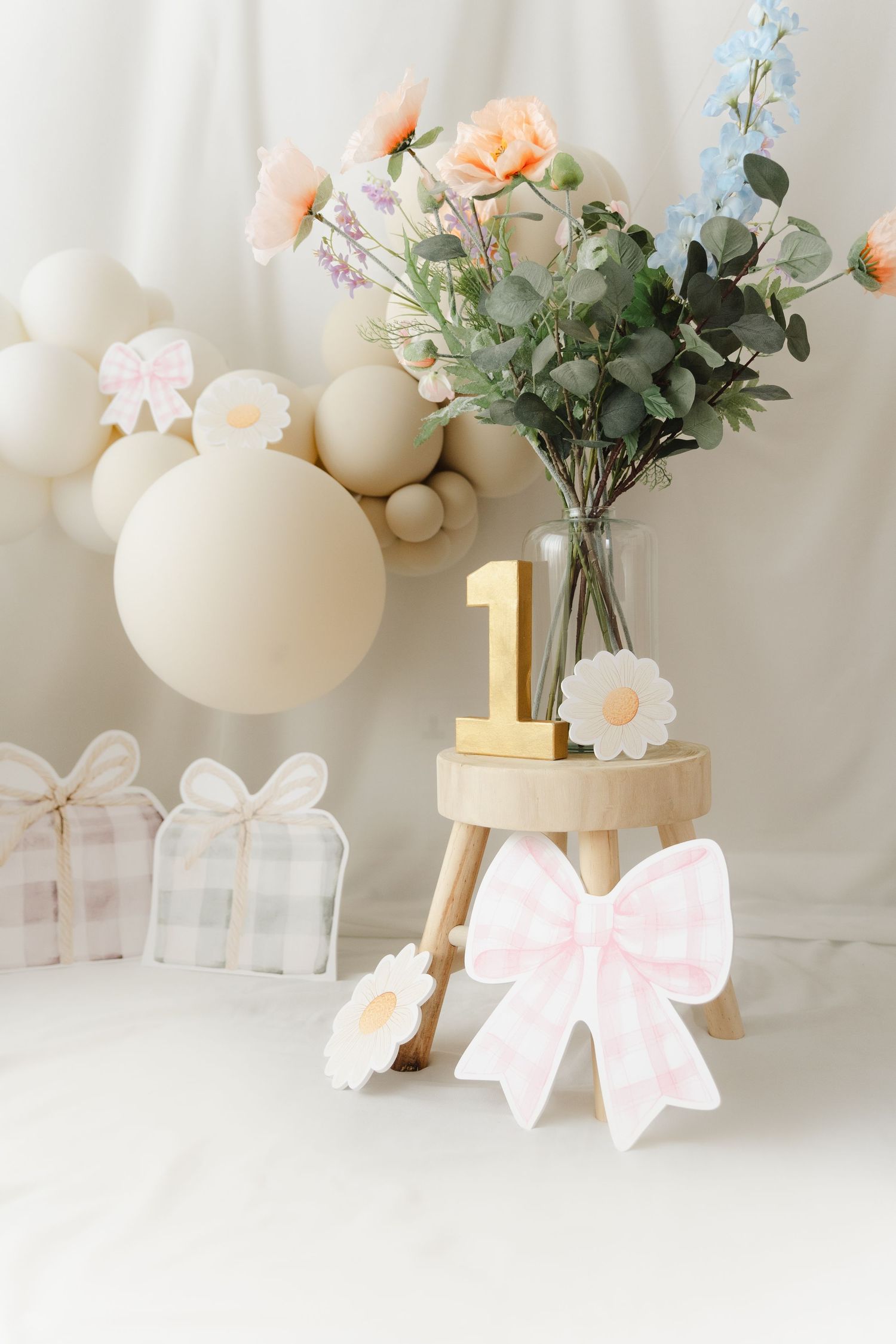 White ceramic vases with gold accents and delicate floral arrangements create an elegant display with soft pink bows.