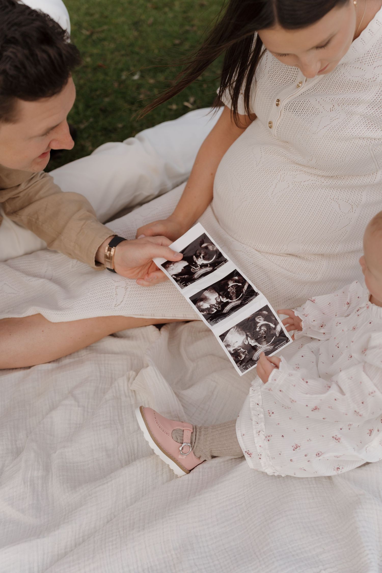 A series of photos showing hands holding ultrasound images on white fabric with scattered rose petals.