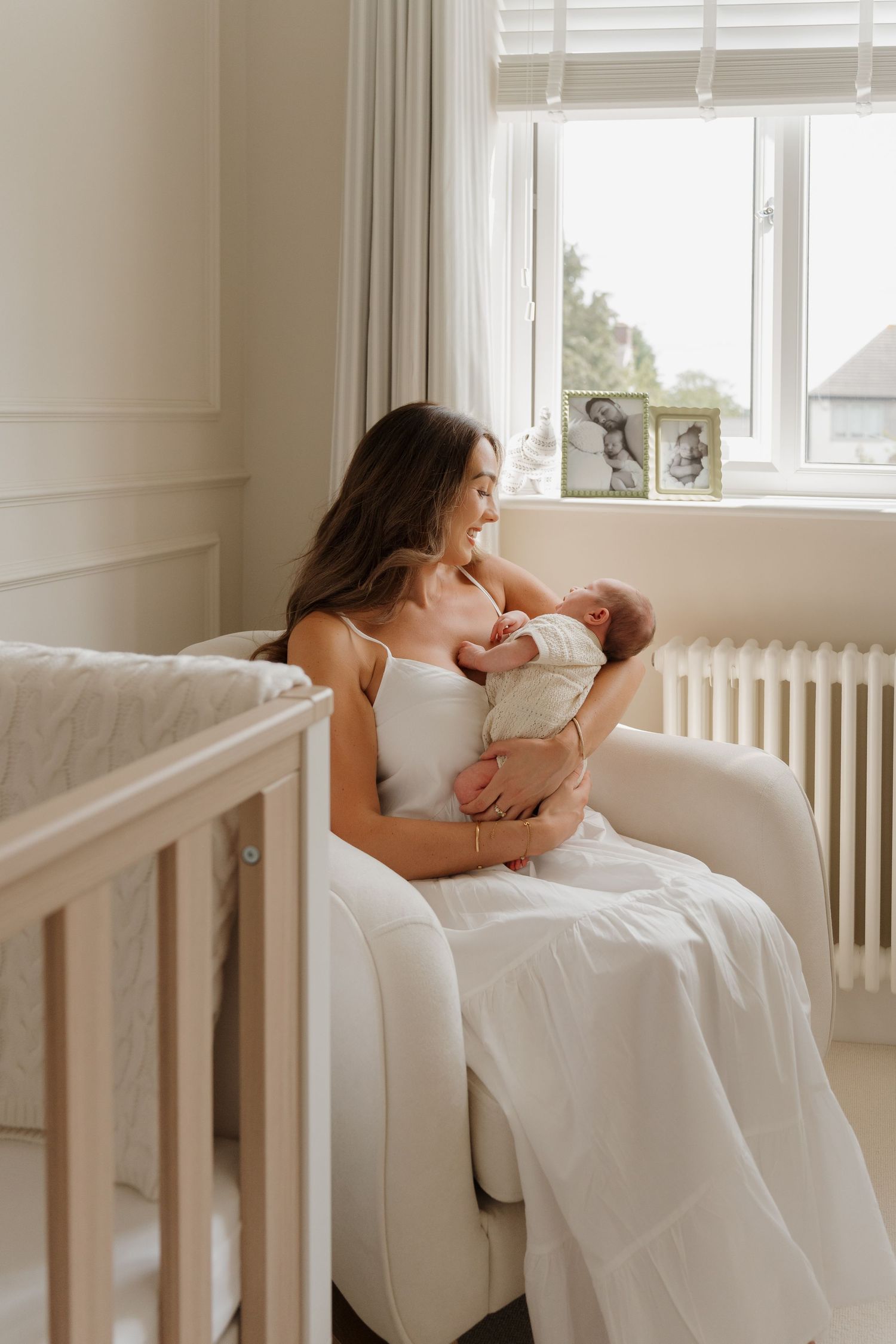Tender moments between parent and newborn in a bright white nursery.