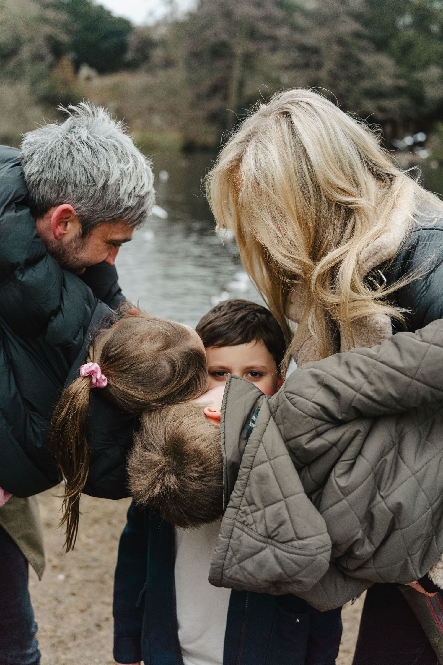 Intimate family moment captured outdoors near a lake.