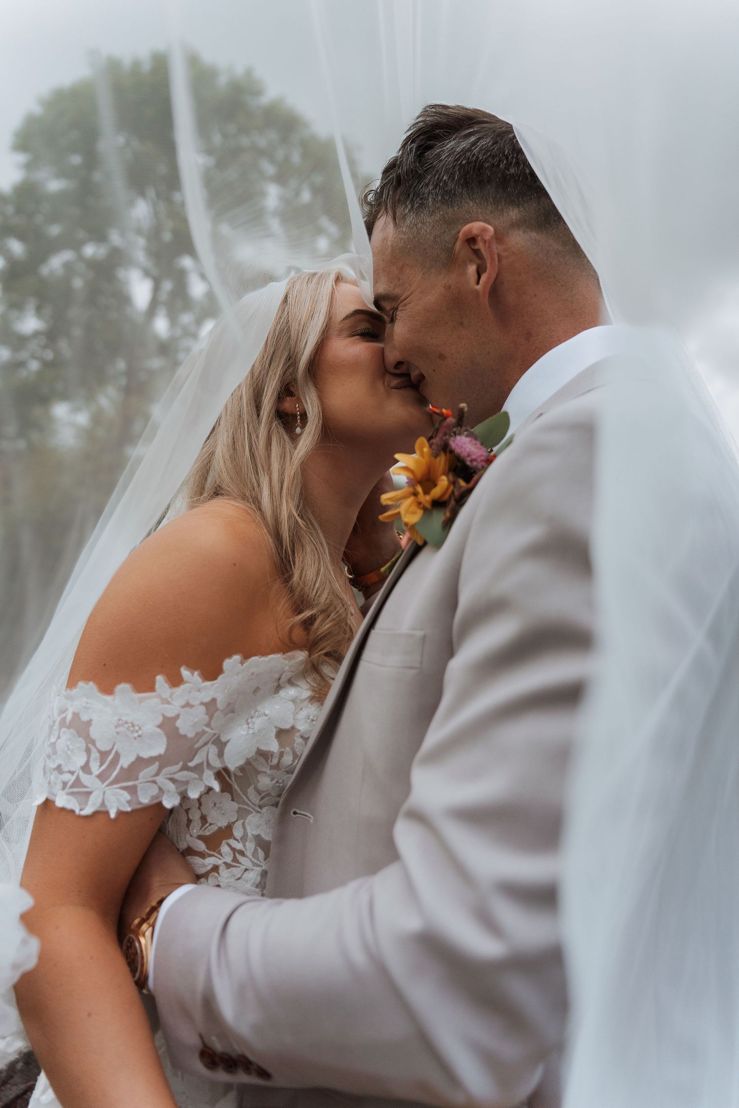 A bride and groom share a romantic kiss under a flowing white veil. Wedding photography in Derbyshire.