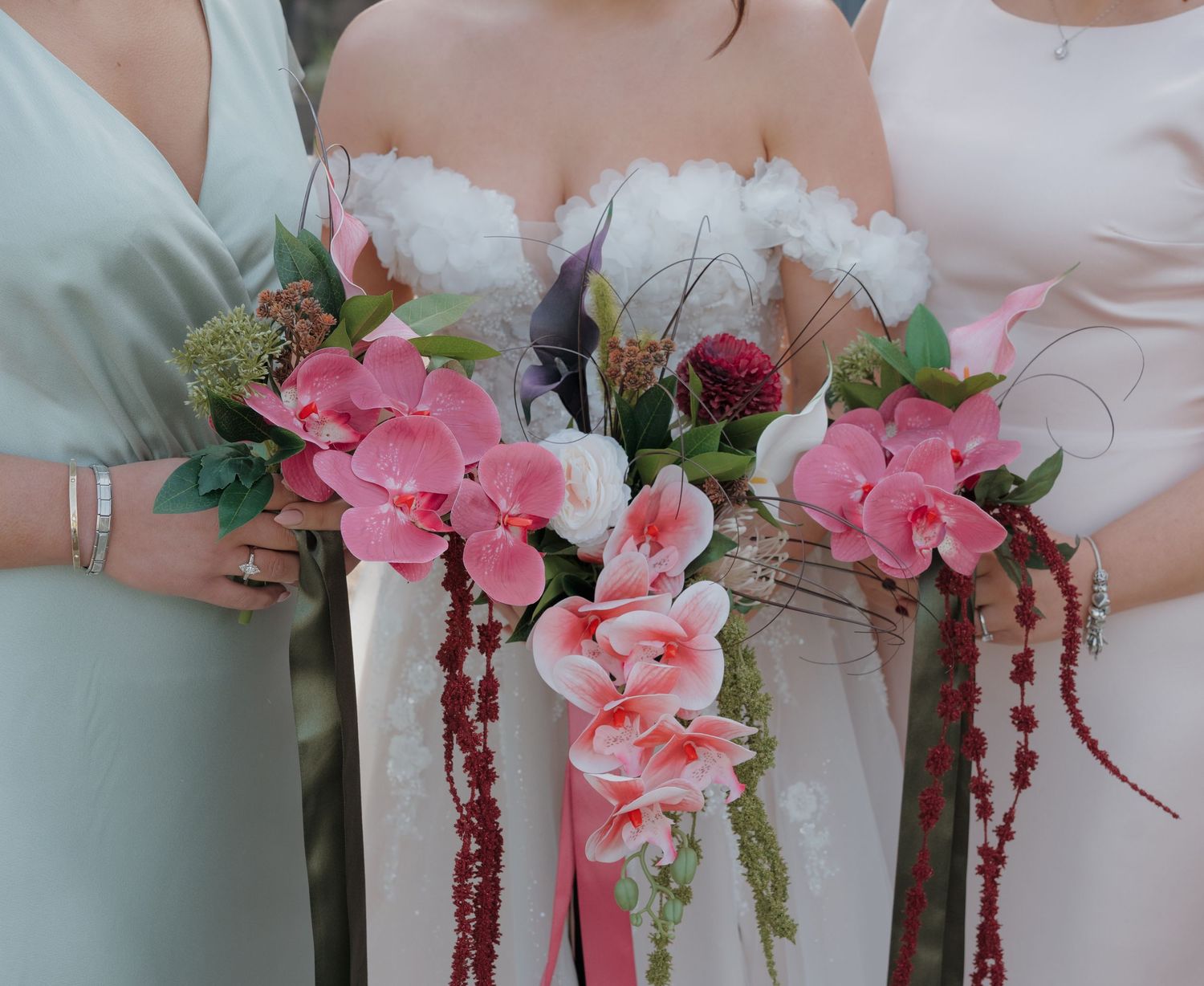 A row of bridesmaids holding pink orchid bouquets with cascading burgundy amaranthus at a wedding ceremony. Wedding photographer in Derby