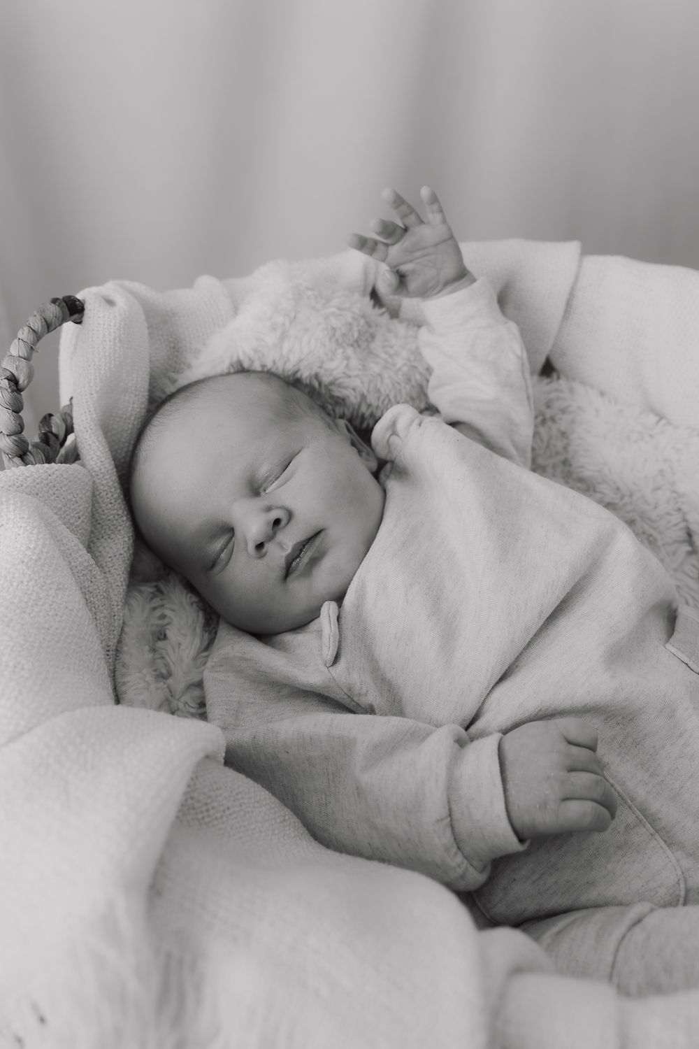 Black and white portrait of sleeping infant wrapped in soft blankets.