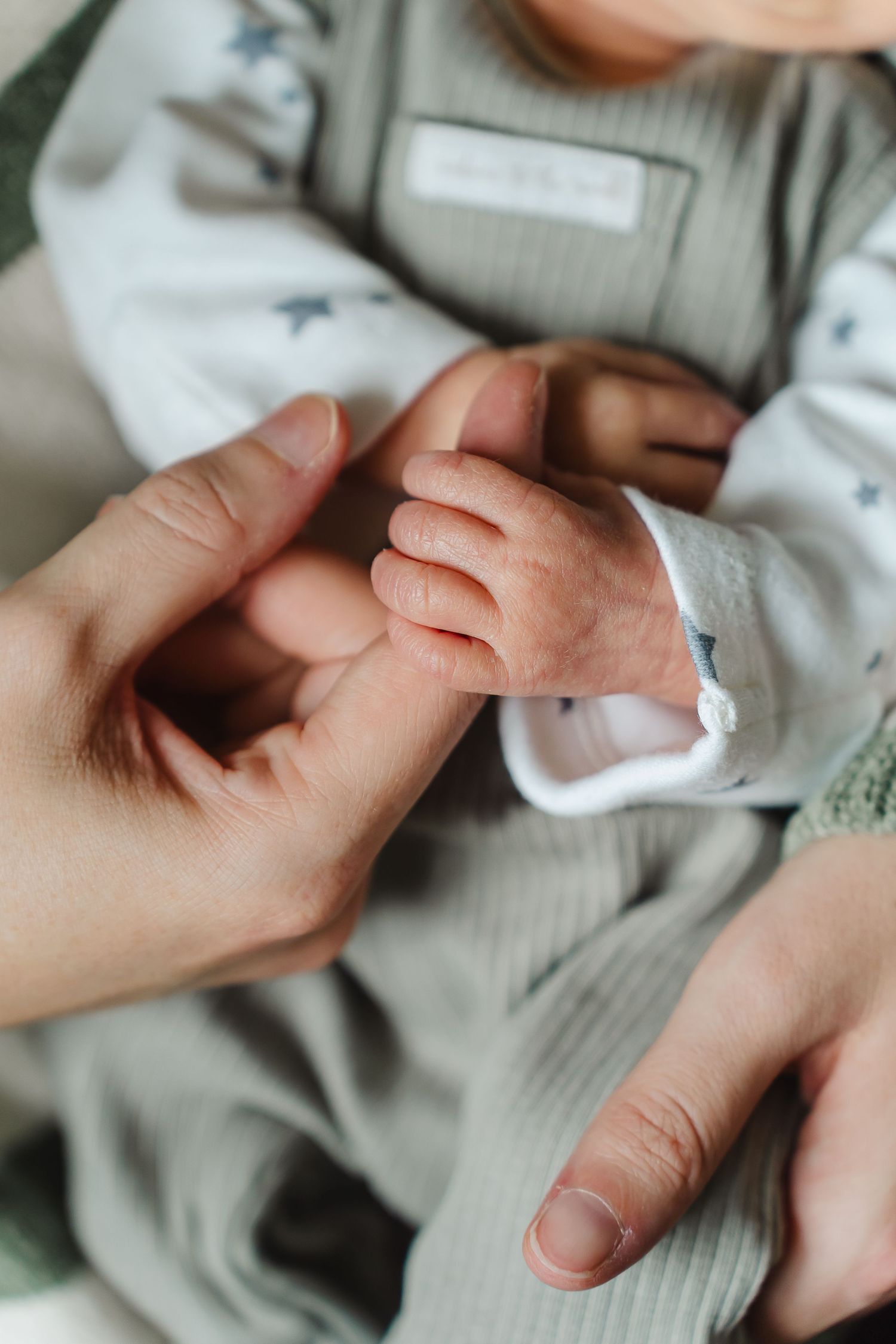 Close-up of gentle hands holding in soft, natural light. Candid and relaxed newborn photography at home in Derbyshire.