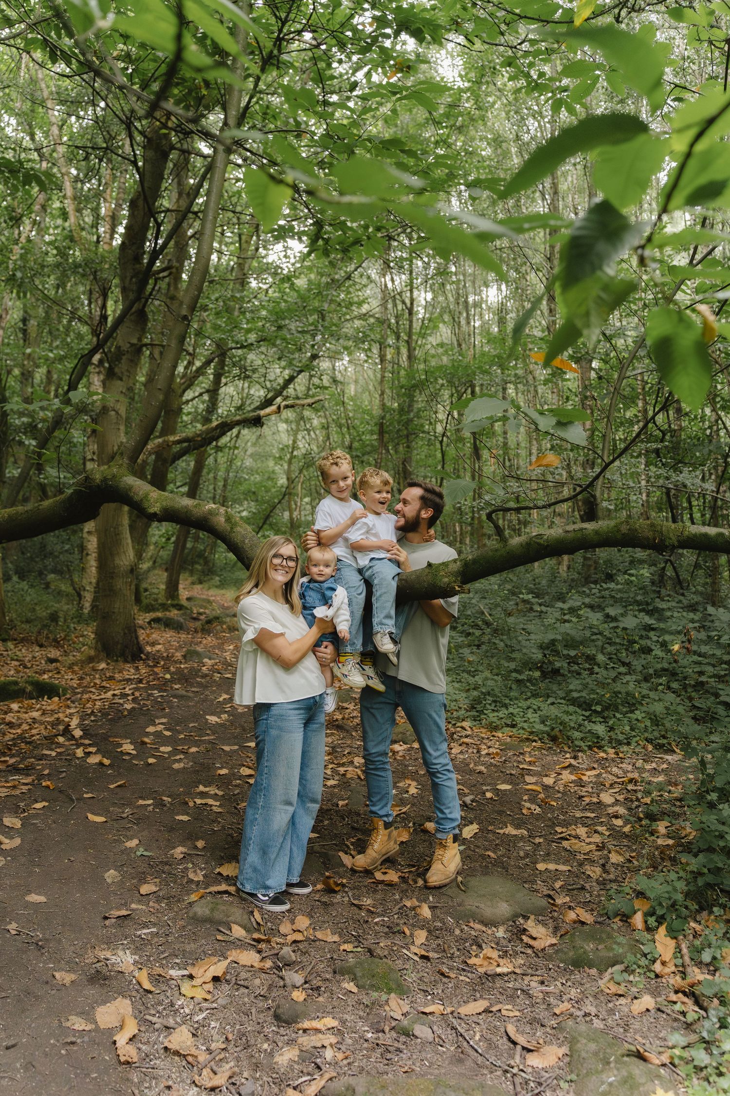 Family enjoying tender moments together on autumn forest path with fallen leaves.