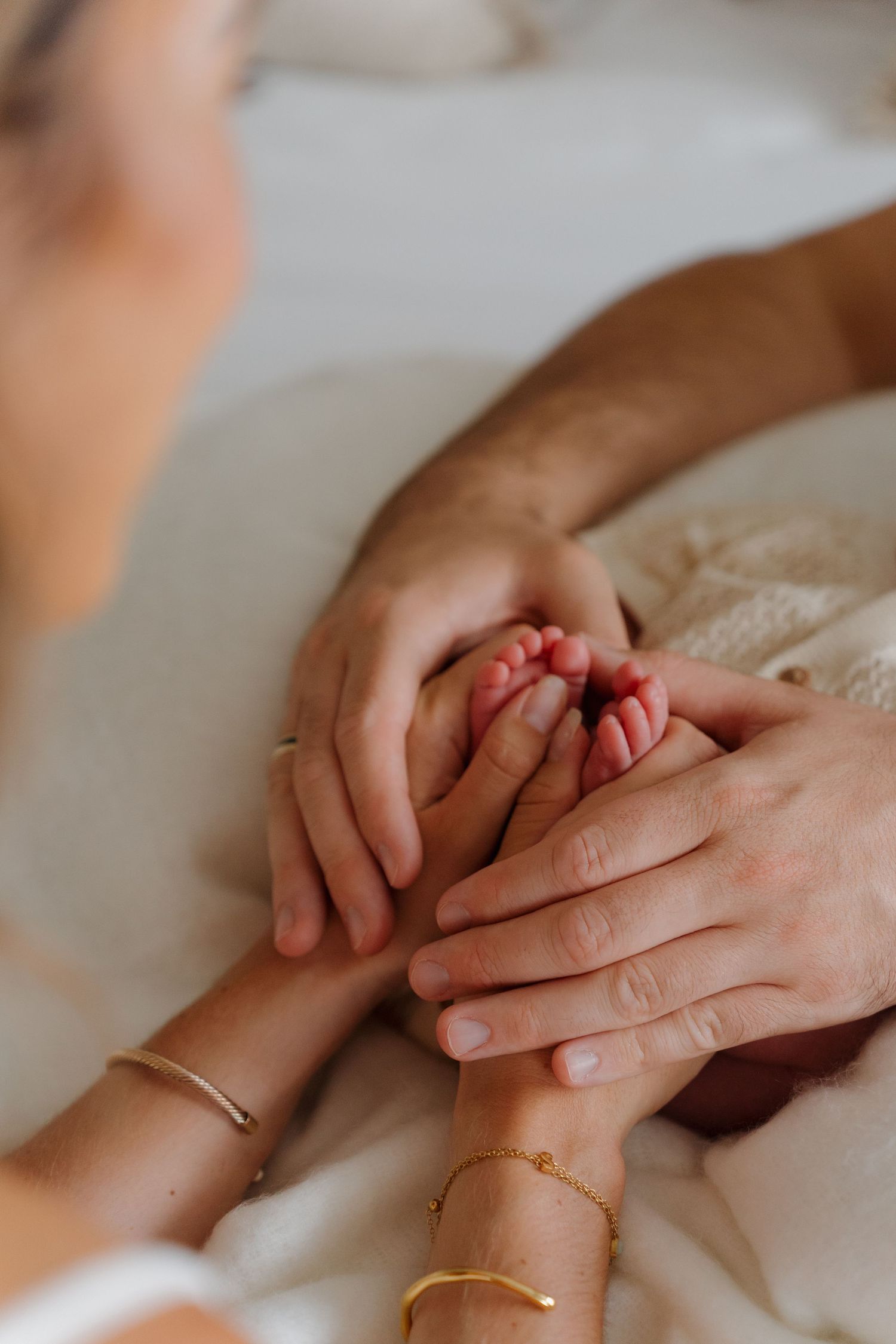 Close-up of gentle hands holding a newborn's tiny fingers.