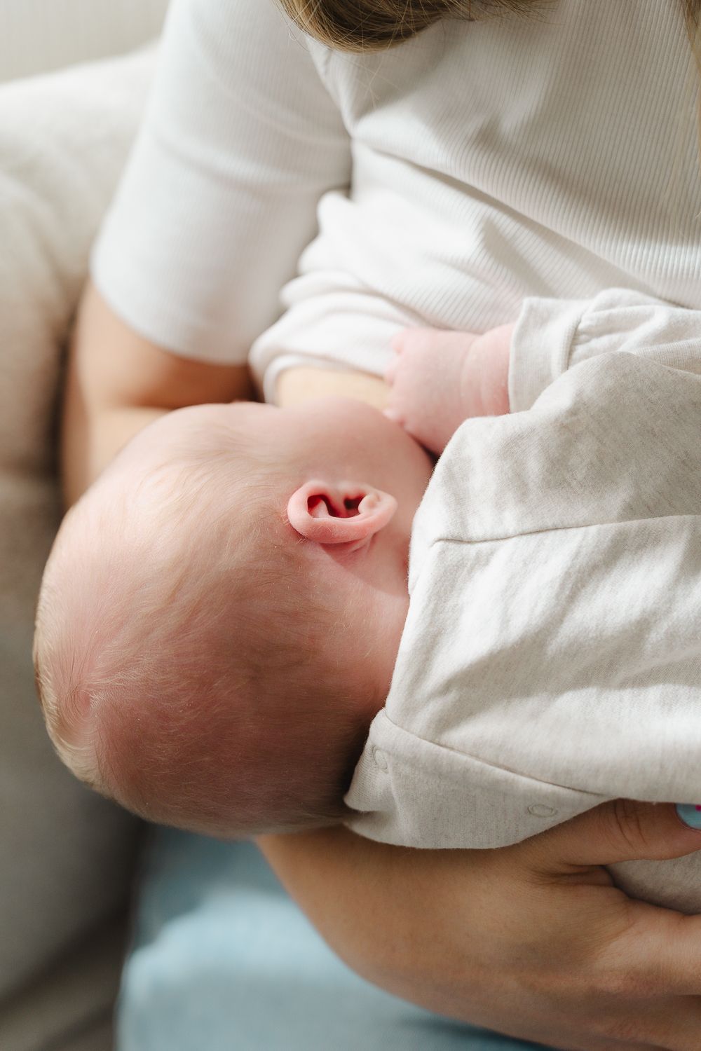 Close-up series showing a newborn baby's tiny hand grasping against a white fabric background.