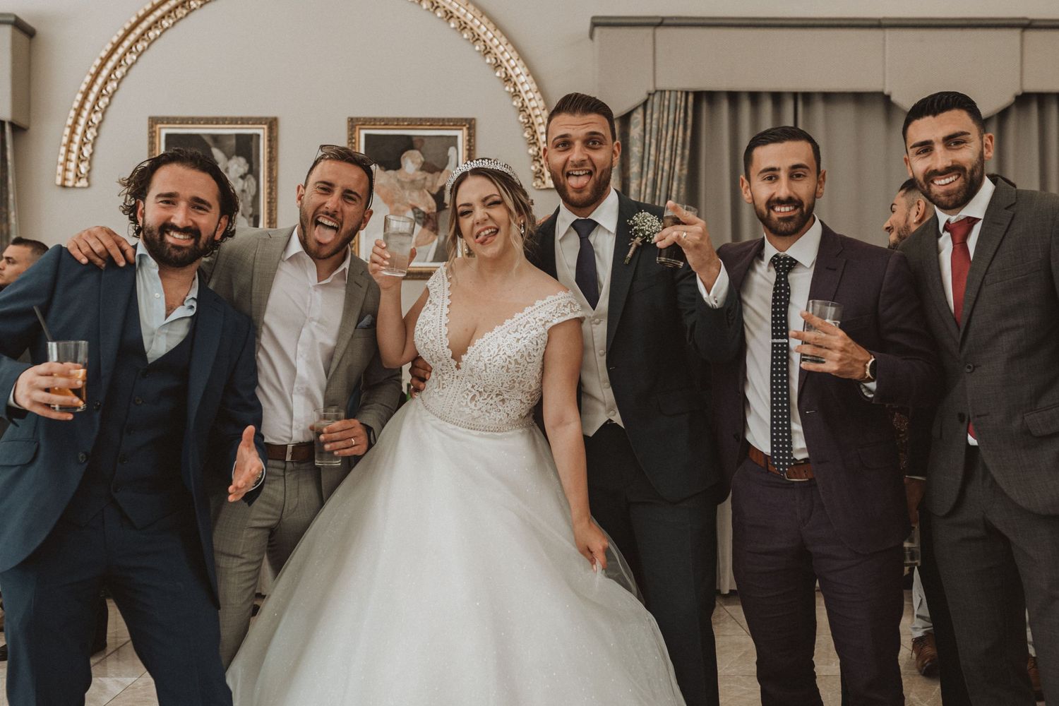 Wedding party in formal attire poses together for celebratory group photo.