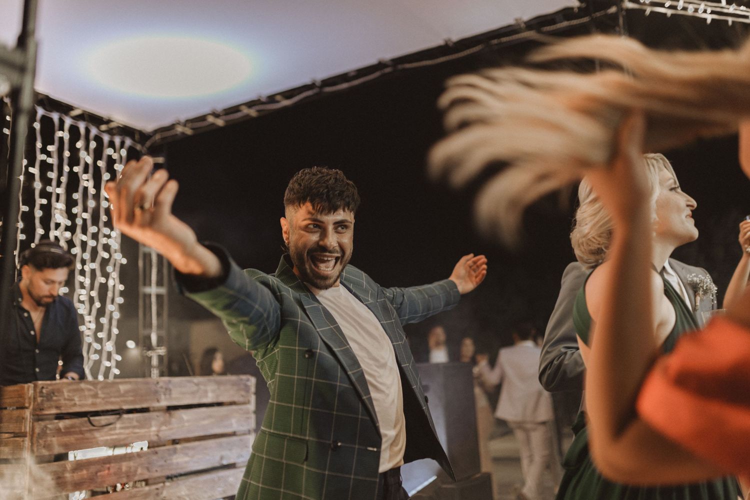 Guests dance and celebrate under twinkling lights at an indoor event.