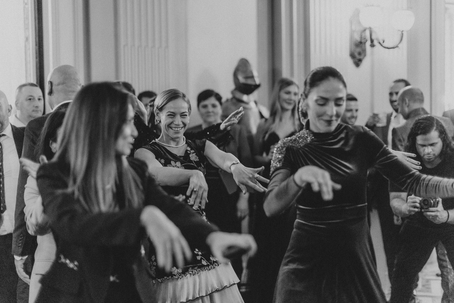 People dancing and celebrating at an elegant indoor wedding reception in black and white.