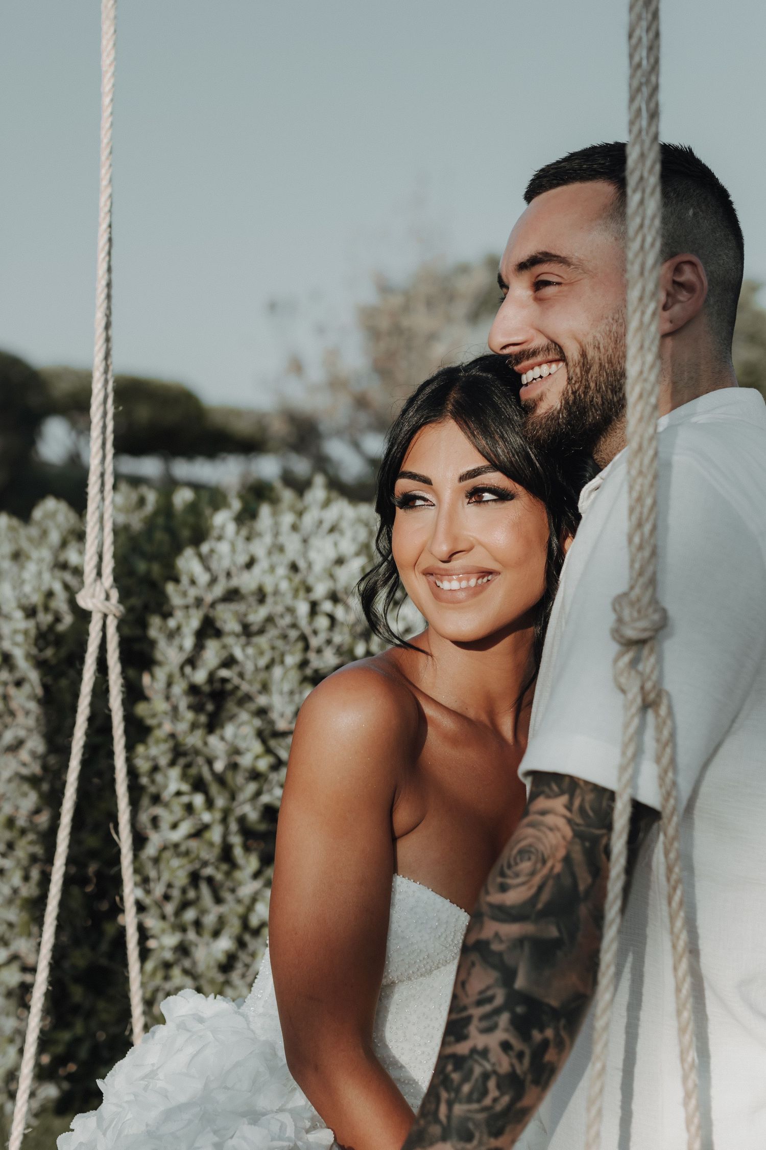 A couple shares a joyful moment together on a rope swing during their wedding photoshoot.