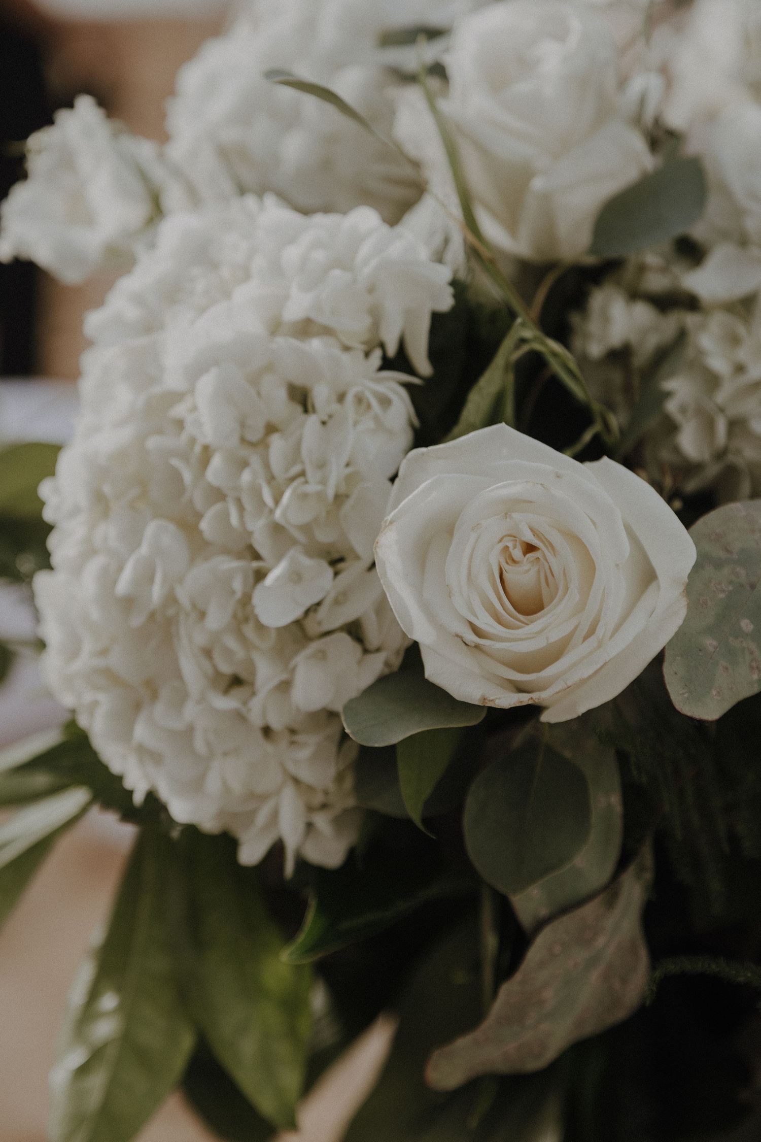 Close-up of elegant white roses and hydrangeas in a wedding floral arrangement.